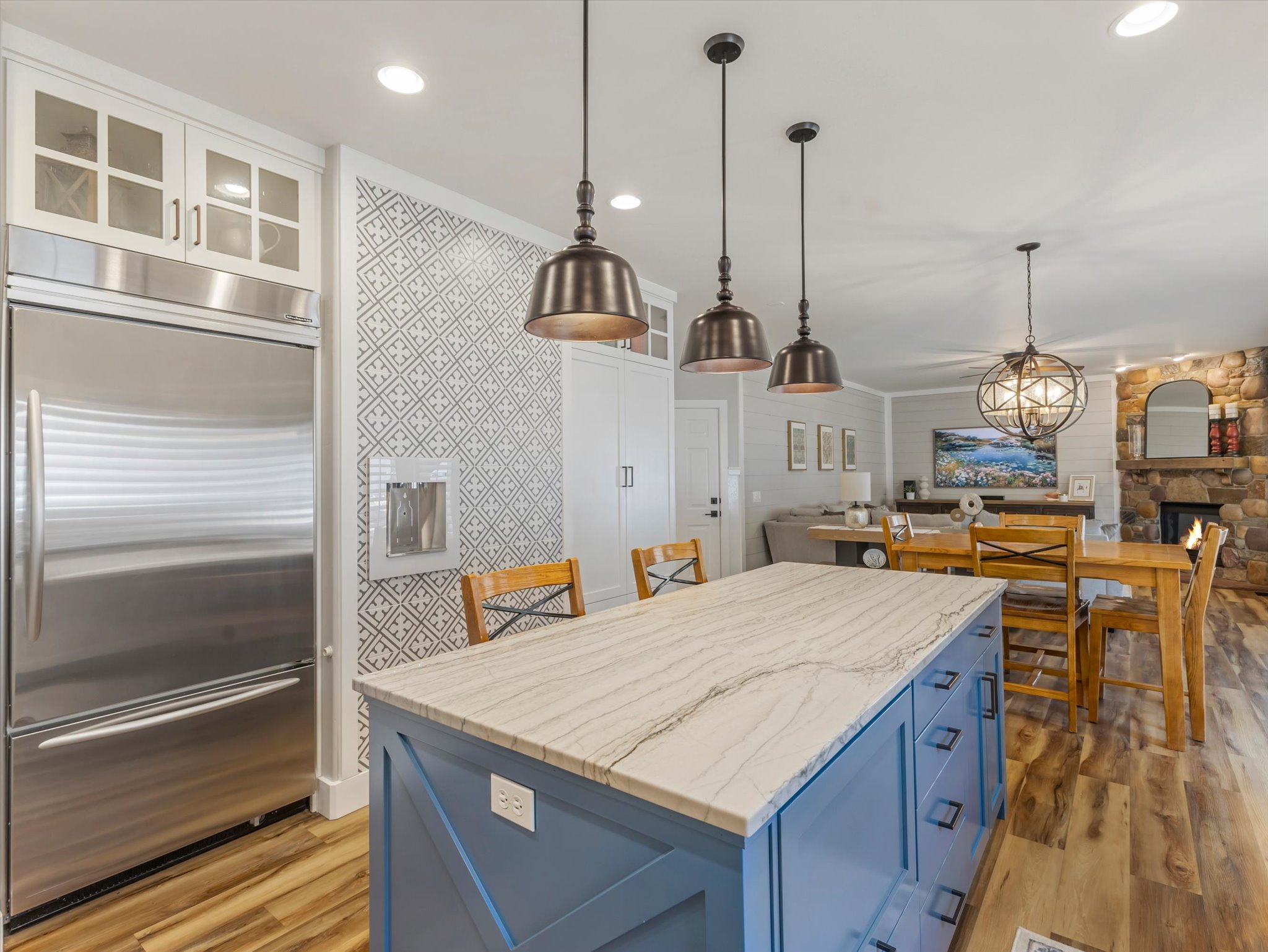 Kitchen with a blue island featuring a light-toned countertop, pendant lighting, and wood-finish flooring