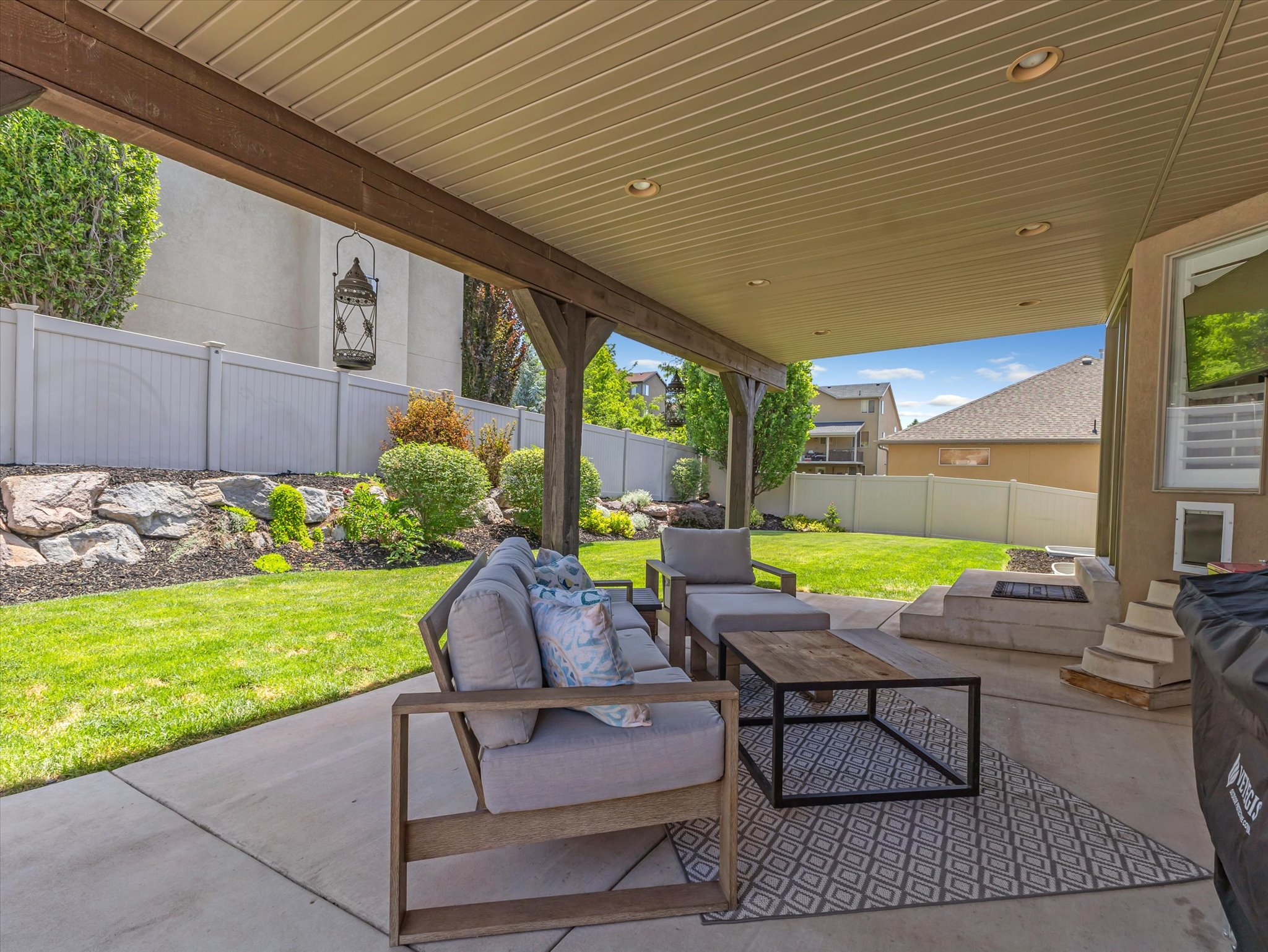 Expansive covered patio featuring a concrete surface, a built-in outdoor fireplace, and recessed lighting
