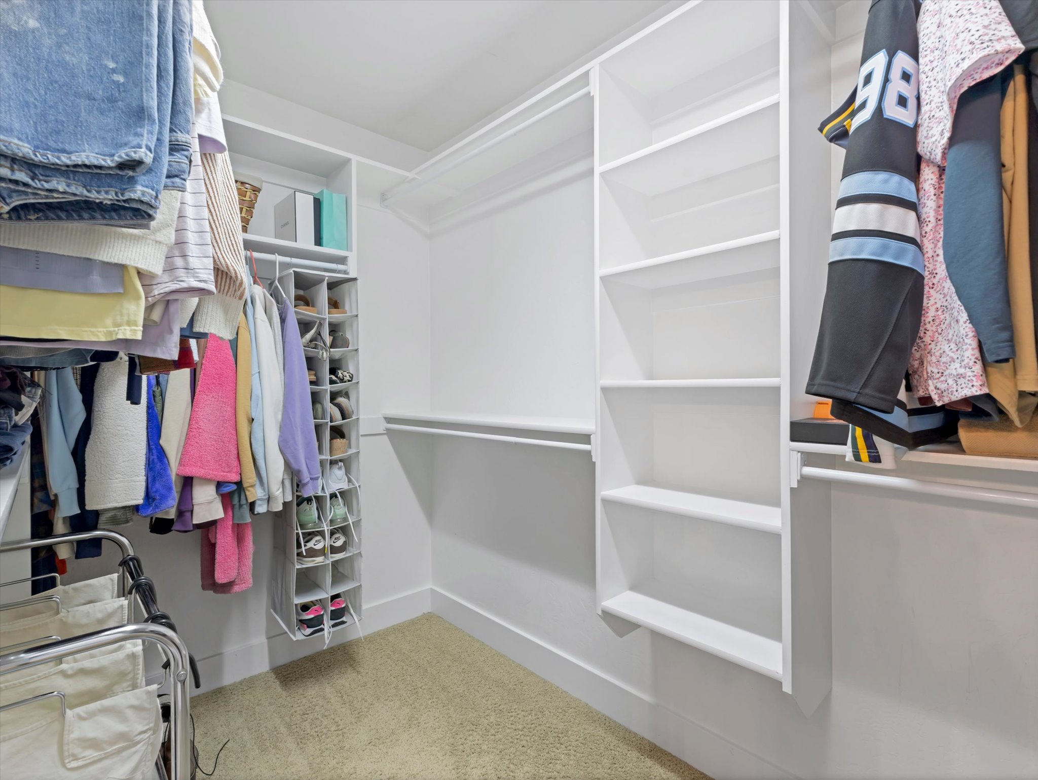 Walk-in closet featuring built-in shelving, white walls, and light-colored carpet flooring