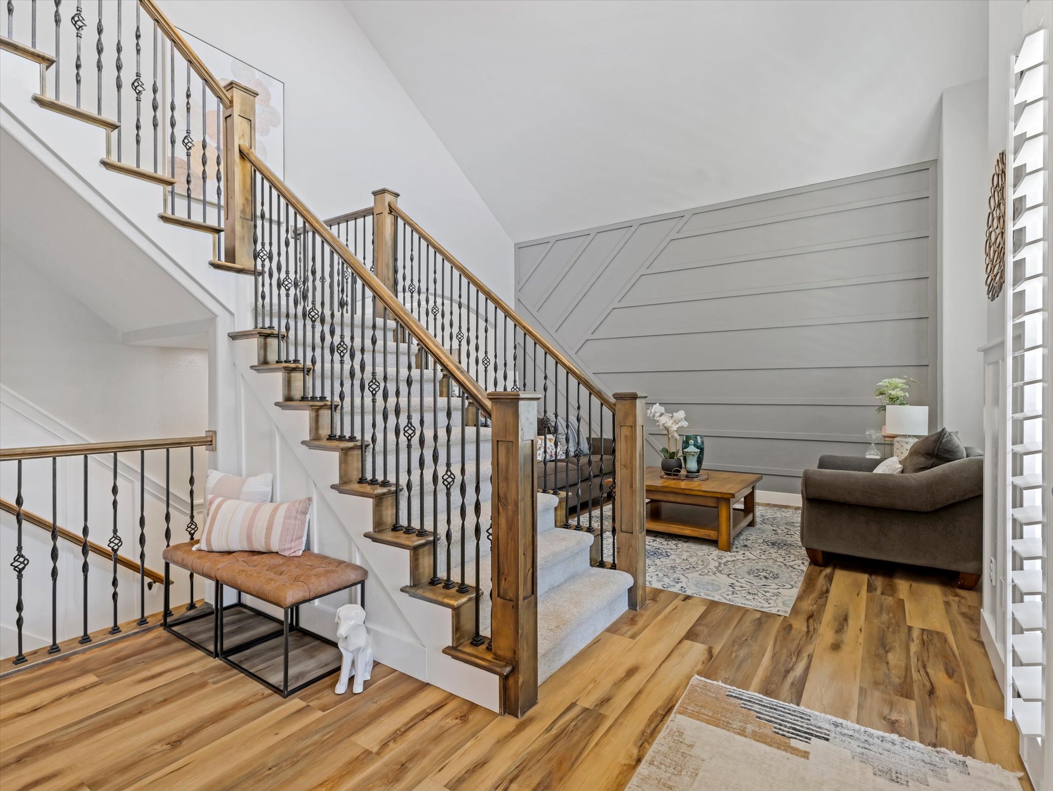 Grand staircase featuring dark metal balusters with decorative elements, wood-finish handrails, and carpeted treads
