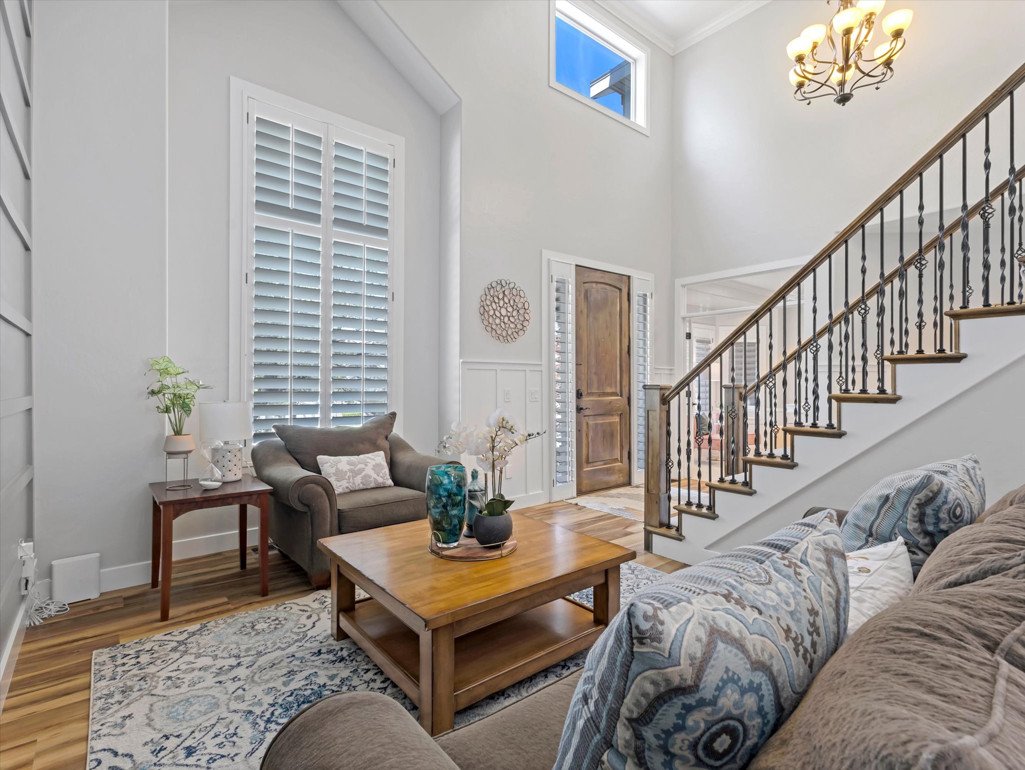 Two-story entryway featuring a wood-finish staircase with wrought iron balusters, high ceilings, and an arched transom window