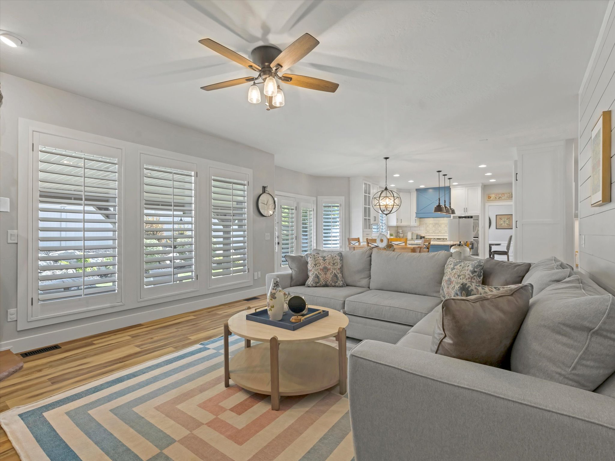 Open concept living area featuring wood-finish flooring and a ceiling fan with integrated lighting