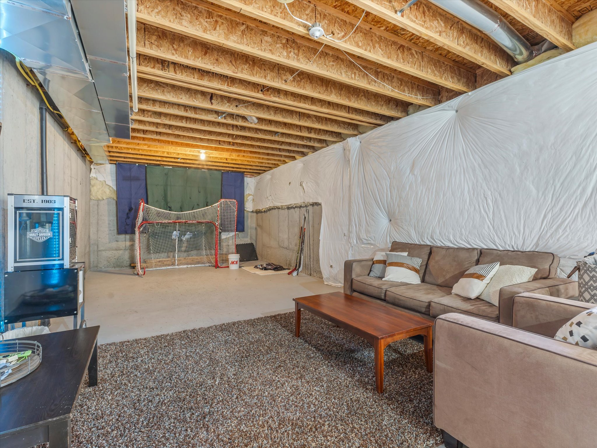 Unfinished basement featuring exposed wood joists and concrete walls