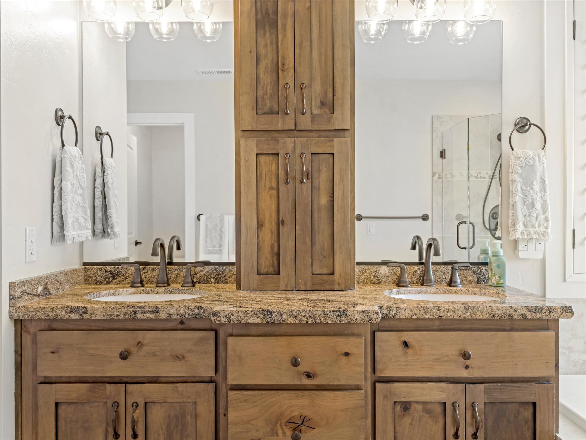 Double vanity with granite countertop, integrated sinks, and bronze-finish fixtures
