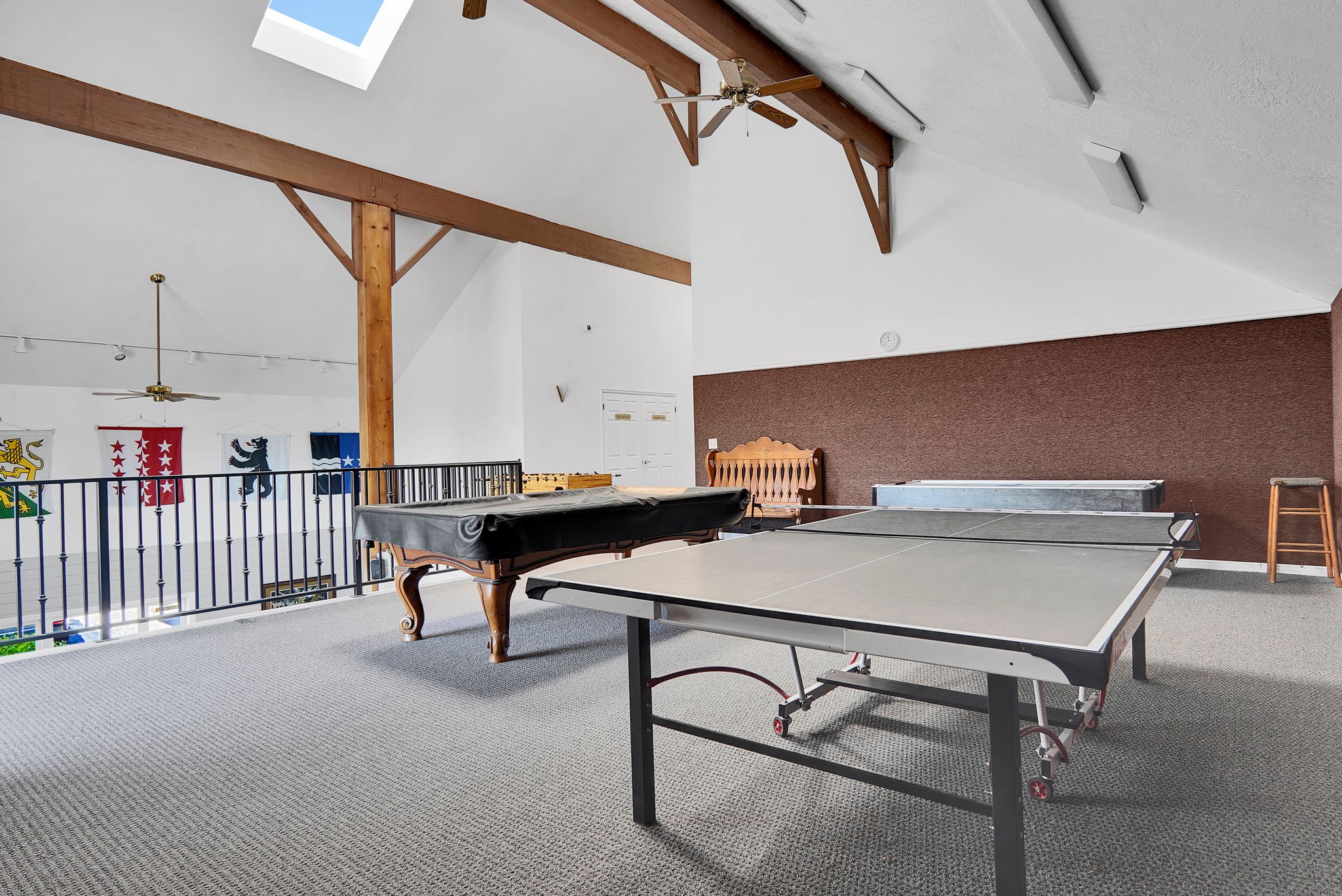 Spacious loft area featuring vaulted ceilings with exposed wood beams, skylight, and wall-to-wall carpeting