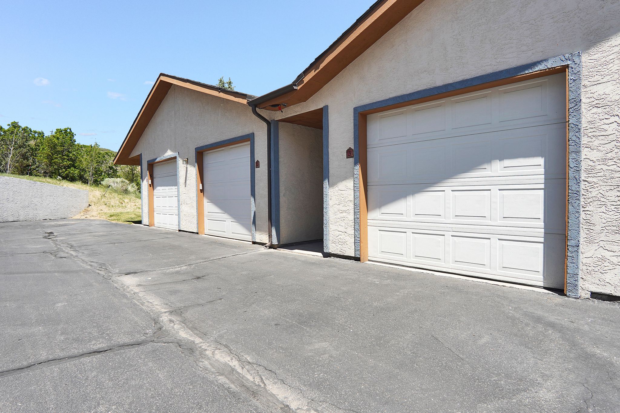 Entry and  garage bay with paneled doors, stucco exterior, and brown trim details