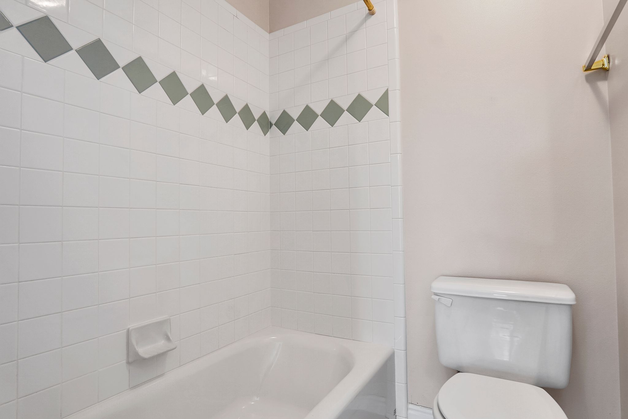 Bathroom featuring a white tiled shower with a decorative accent band