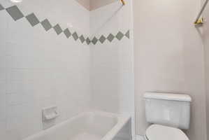 Bathroom featuring a white tiled shower with a decorative accent band
