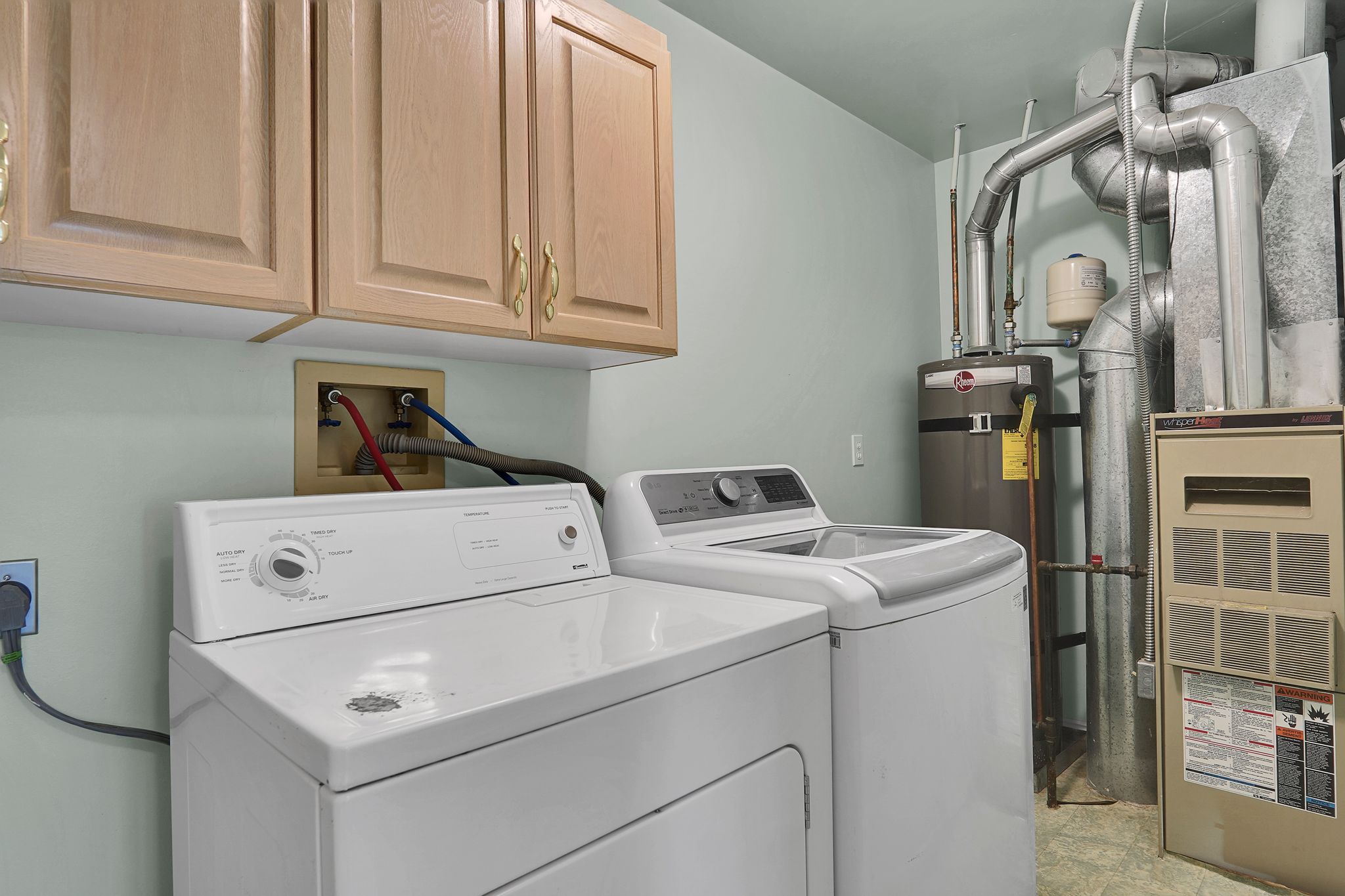 Dedicated laundry area featuring light wood-finish cabinetry, a utility sink connection, and durable flooring