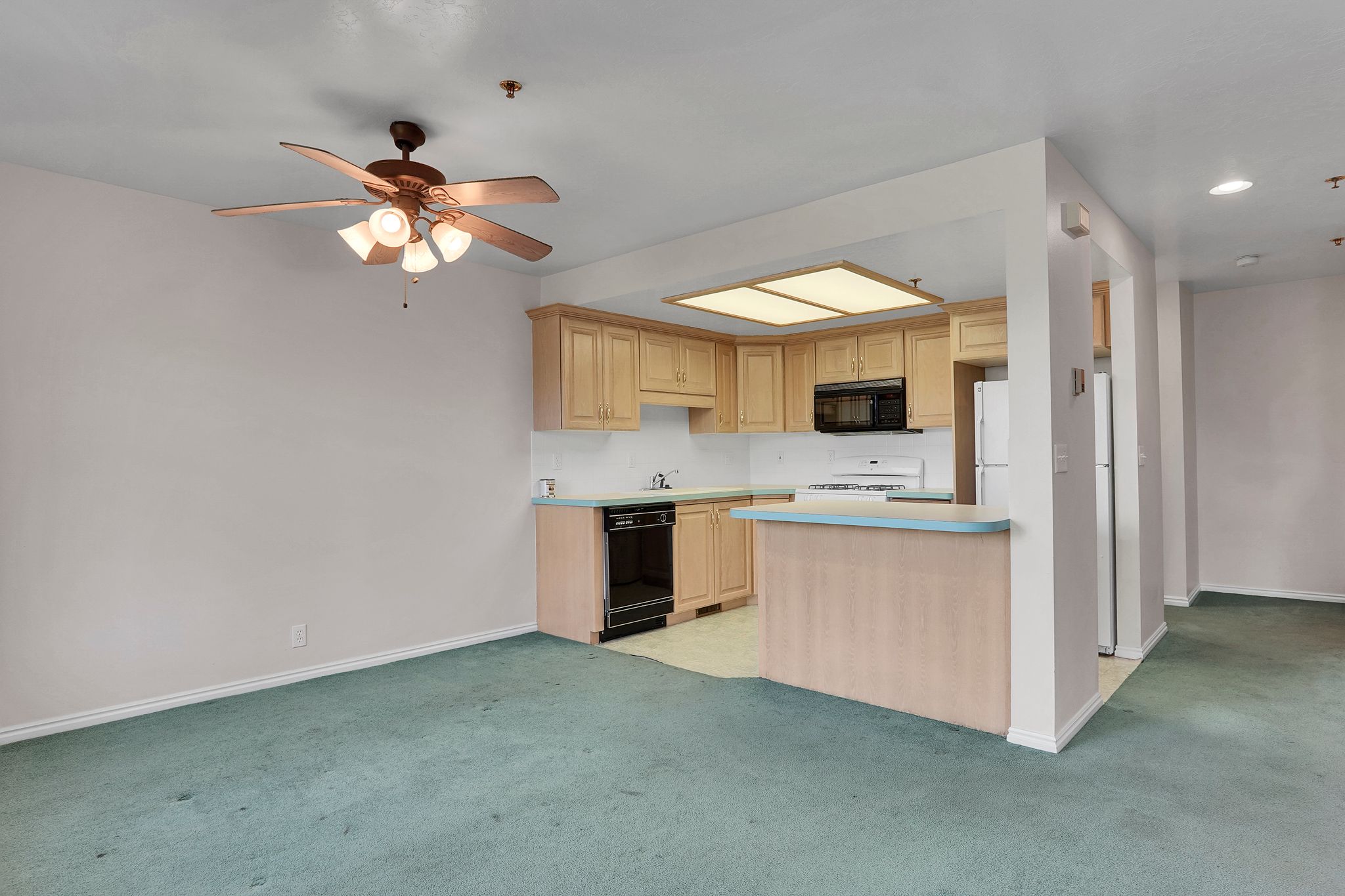 Kitchen featuring light wood cabinetry, white countertops, and a black built-in microwave