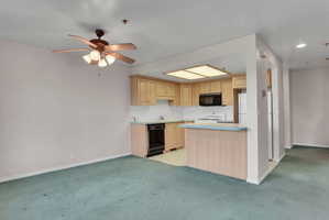 Kitchen featuring light wood cabinetry, white countertops, and a black built-in microwave