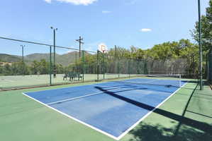 Pickleball court featuring a surface with white boundary lines.  Tennis courts in the background (under repari)