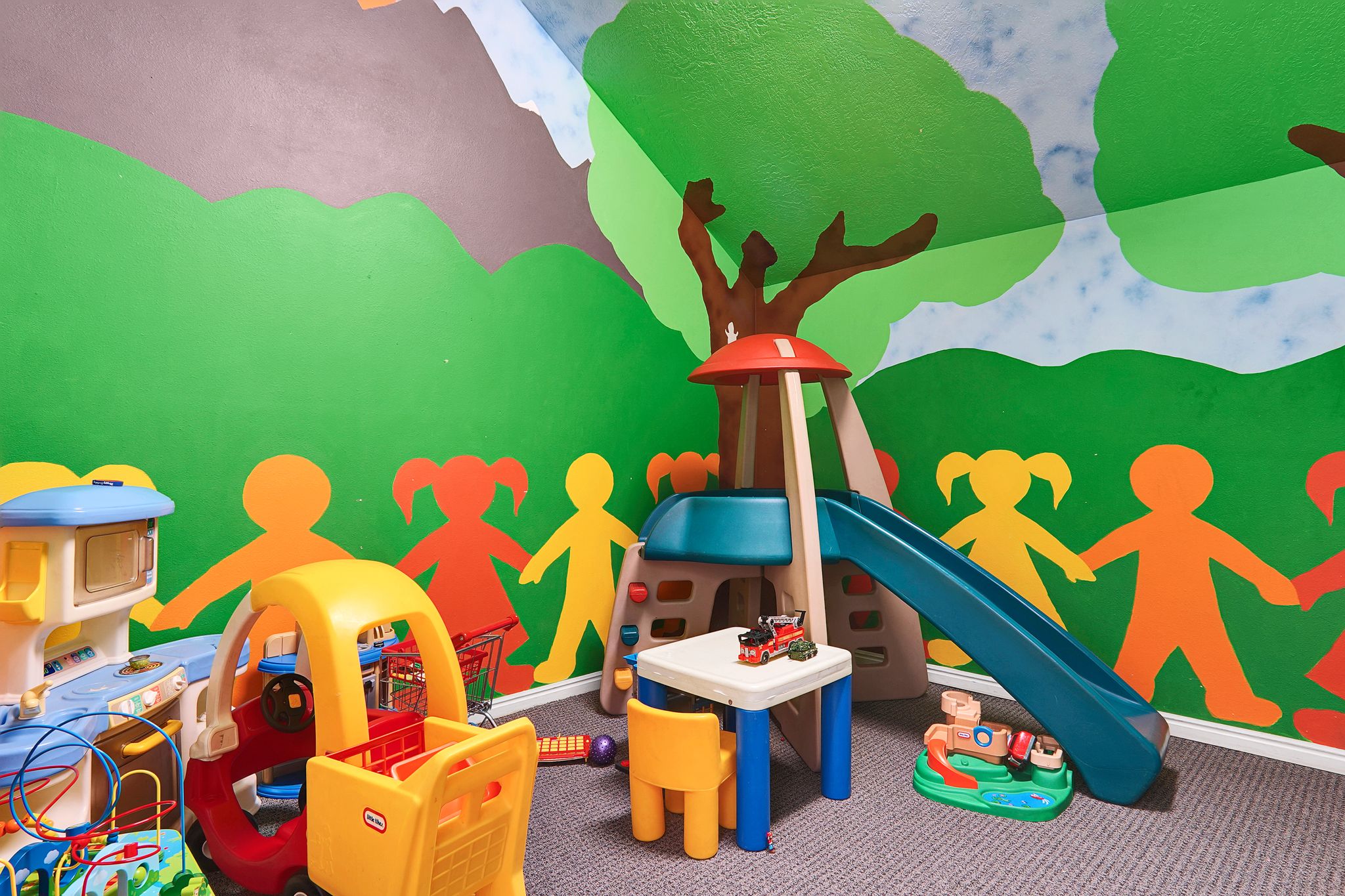 Clubhouse Kid's Room featuring vibrant wall murals, sloped ceiling details, and neutral carpet flooring