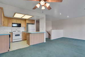 Kitchen featuring natural wood-finish cabinetry, white tile backsplash, a white electric range, and a breakfast bar with light blue countertops