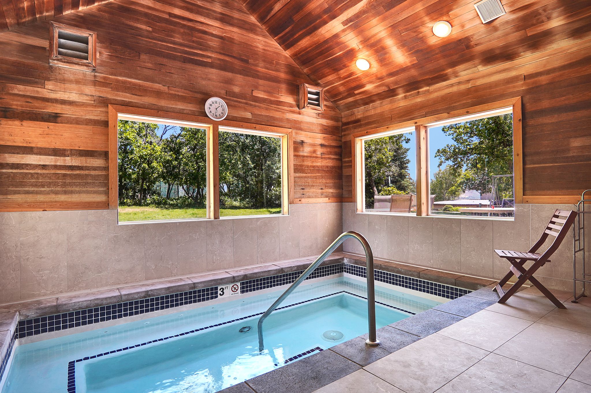 Indoor spa tub featuring a stainless steel grab rail and blue and white tile accents