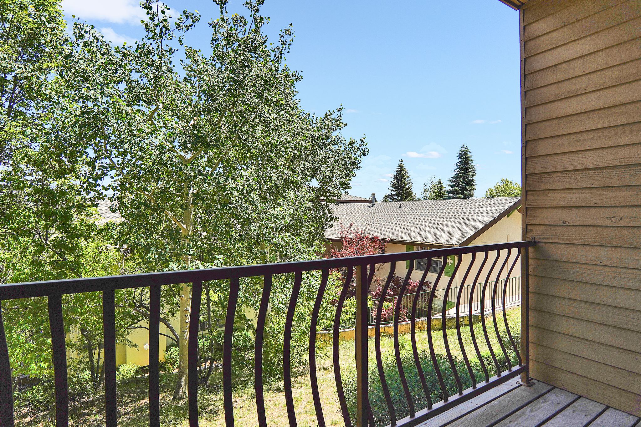 Balcony featuring wood-finish decking and a black wrought iron railing with curved balusters