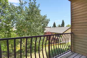 Balcony featuring wood-finish decking and a black wrought iron railing with curved balusters