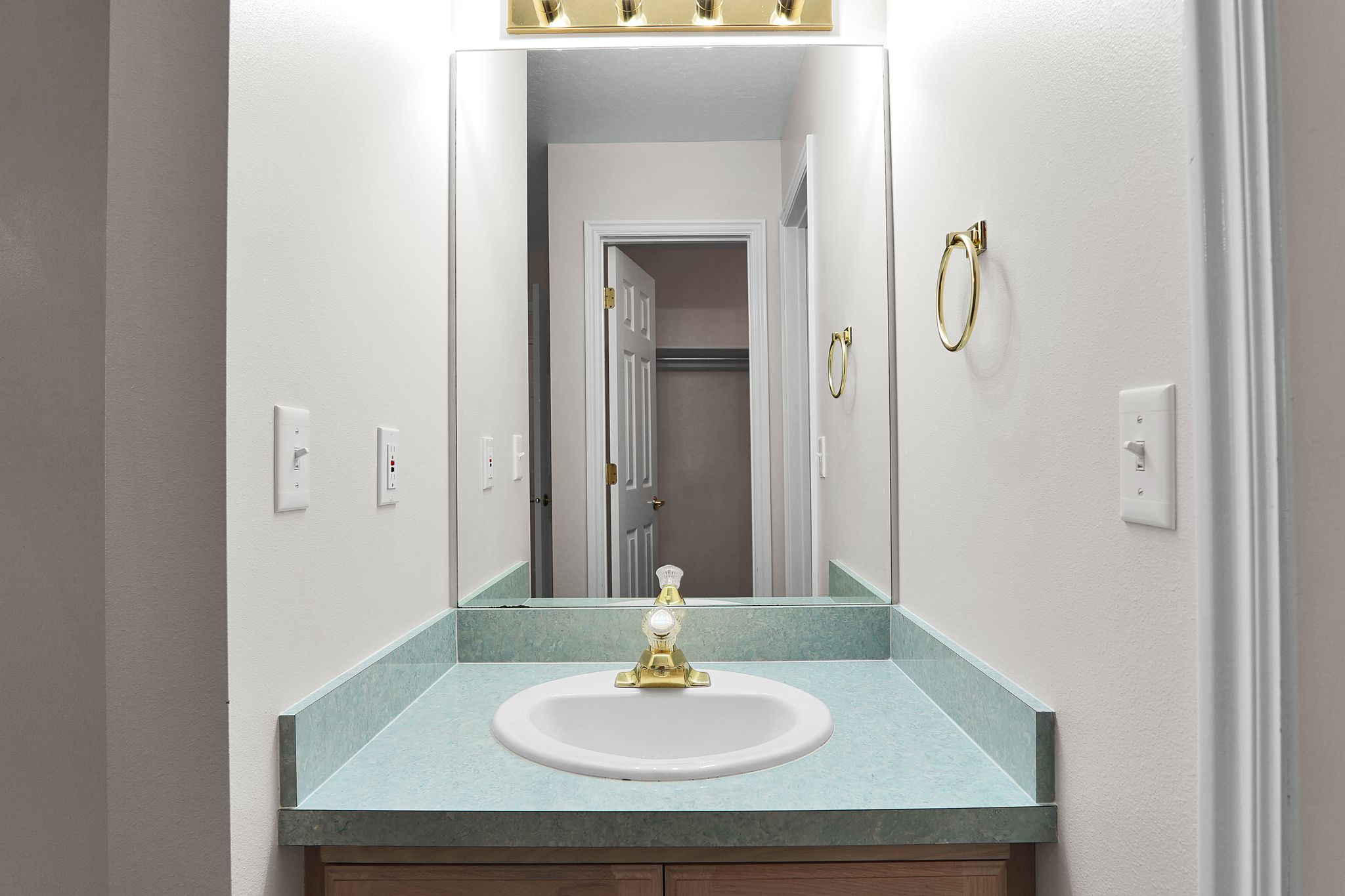Vanity featuring an integrated oval sink, light blue countertop, and a brass-finish faucet