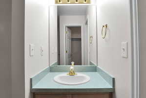 Vanity featuring an integrated oval sink, light blue countertop, and a brass-finish faucet