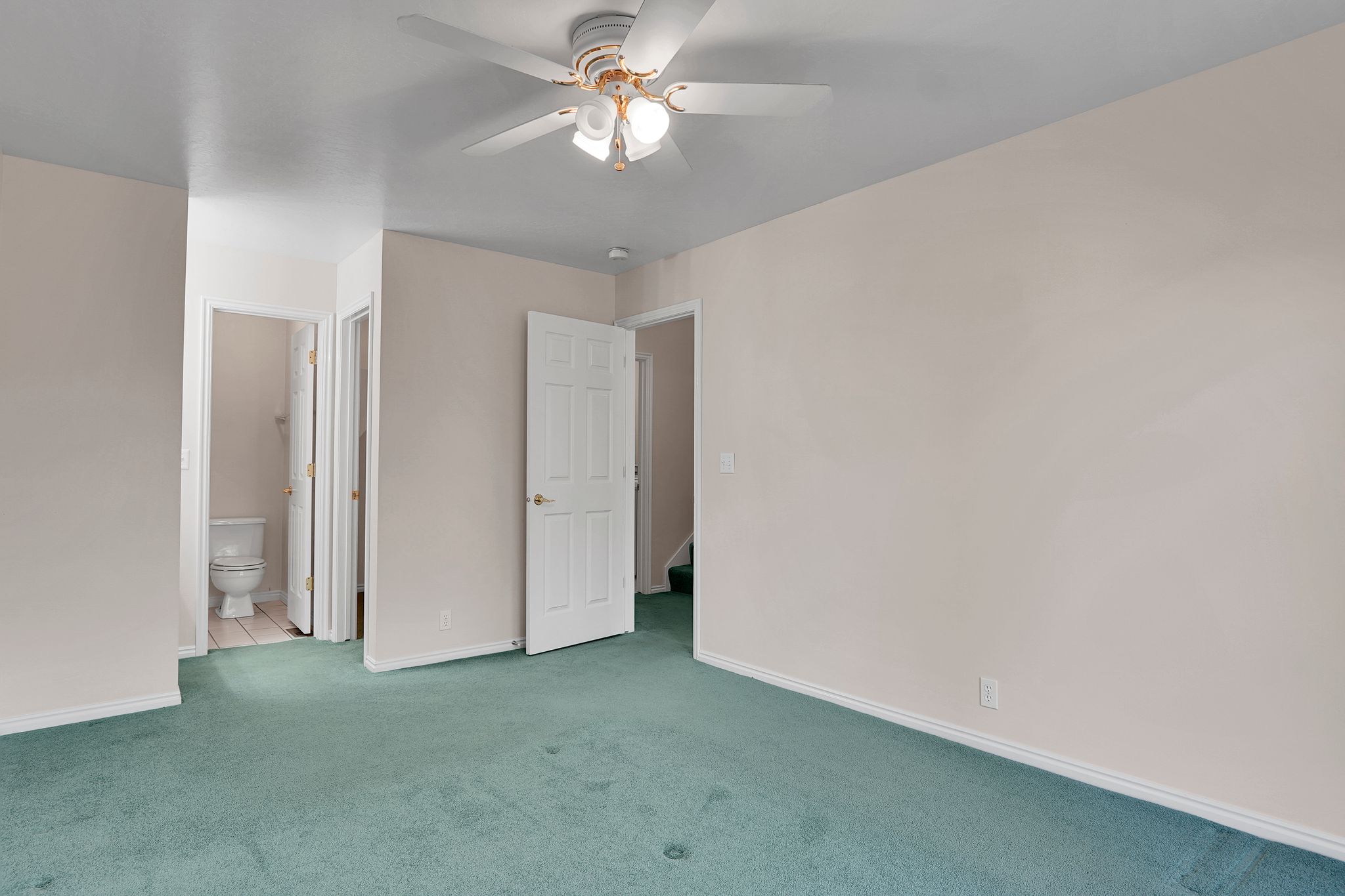 Spacious room featuring light-toned walls and green carpeting