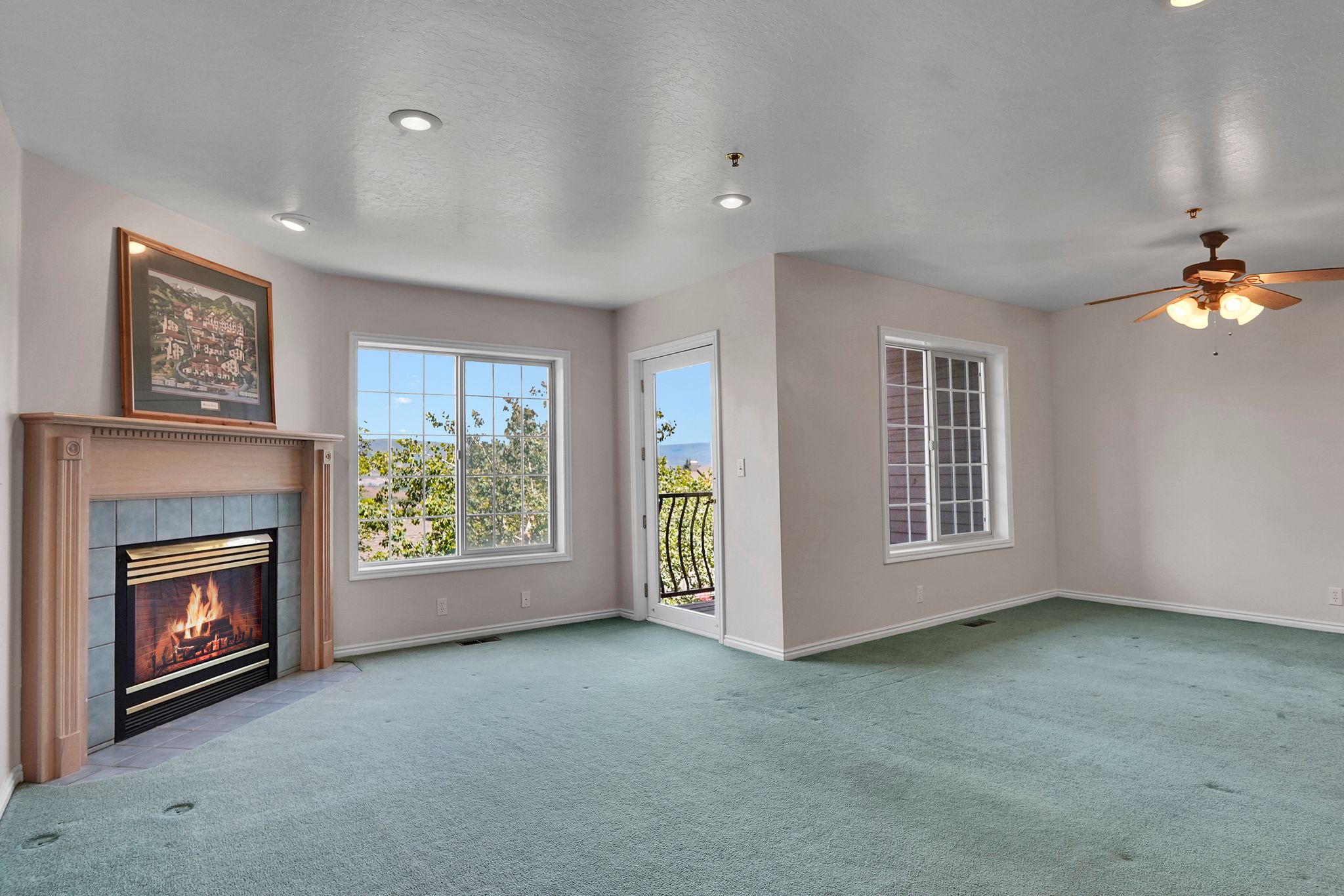 Living space featuring a fireplace with a wood mantle and tile surround, recessed lighting, and a ceiling fan