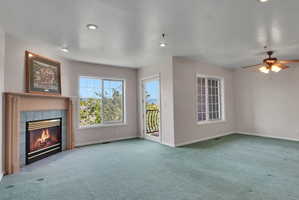 Living space featuring a fireplace with a wood mantle and tile surround, recessed lighting, and a ceiling fan