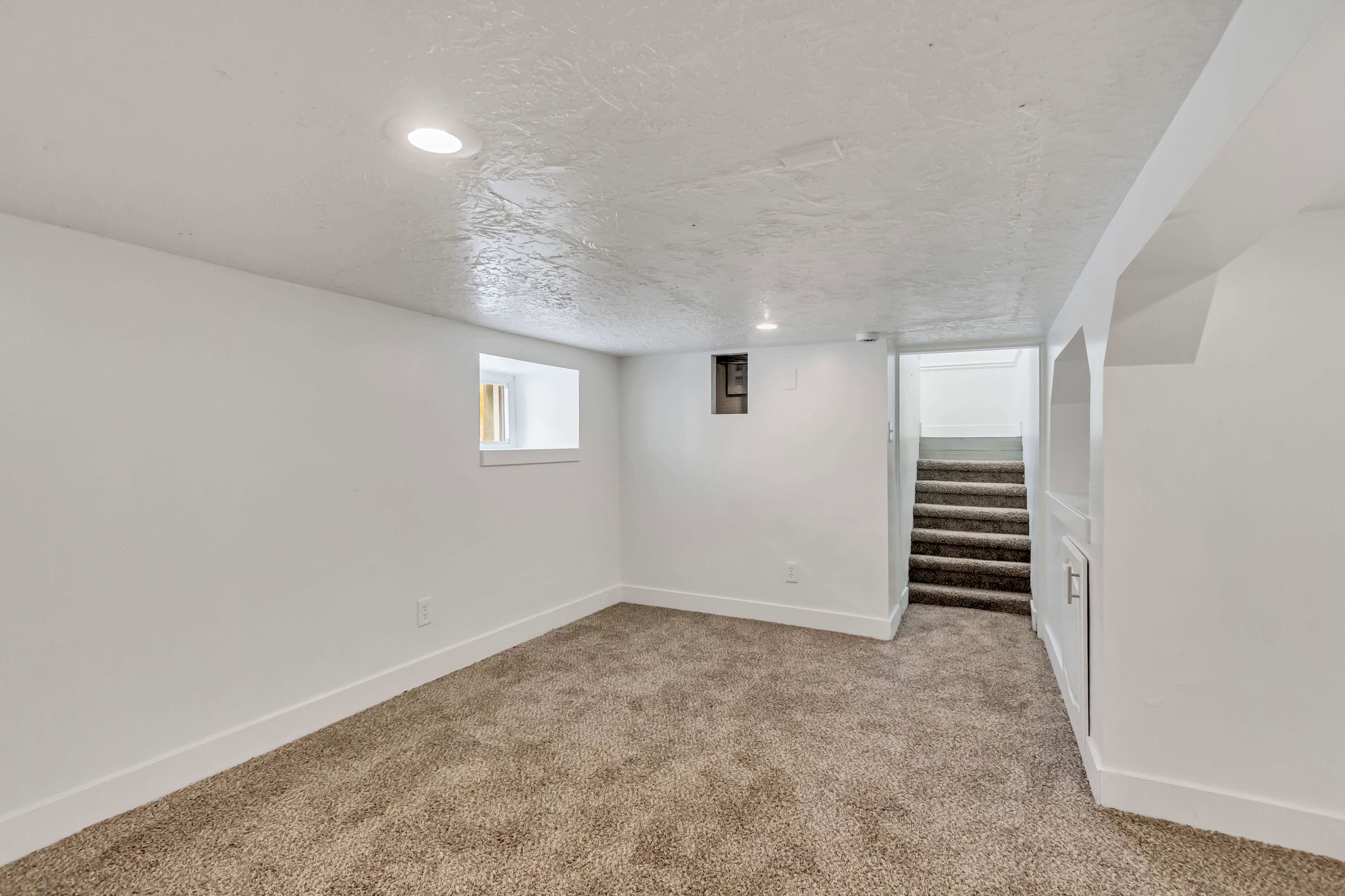 Carpeted room featuring recessed lighting, a white painted window frame, built-in shelving, and a carpeted staircase