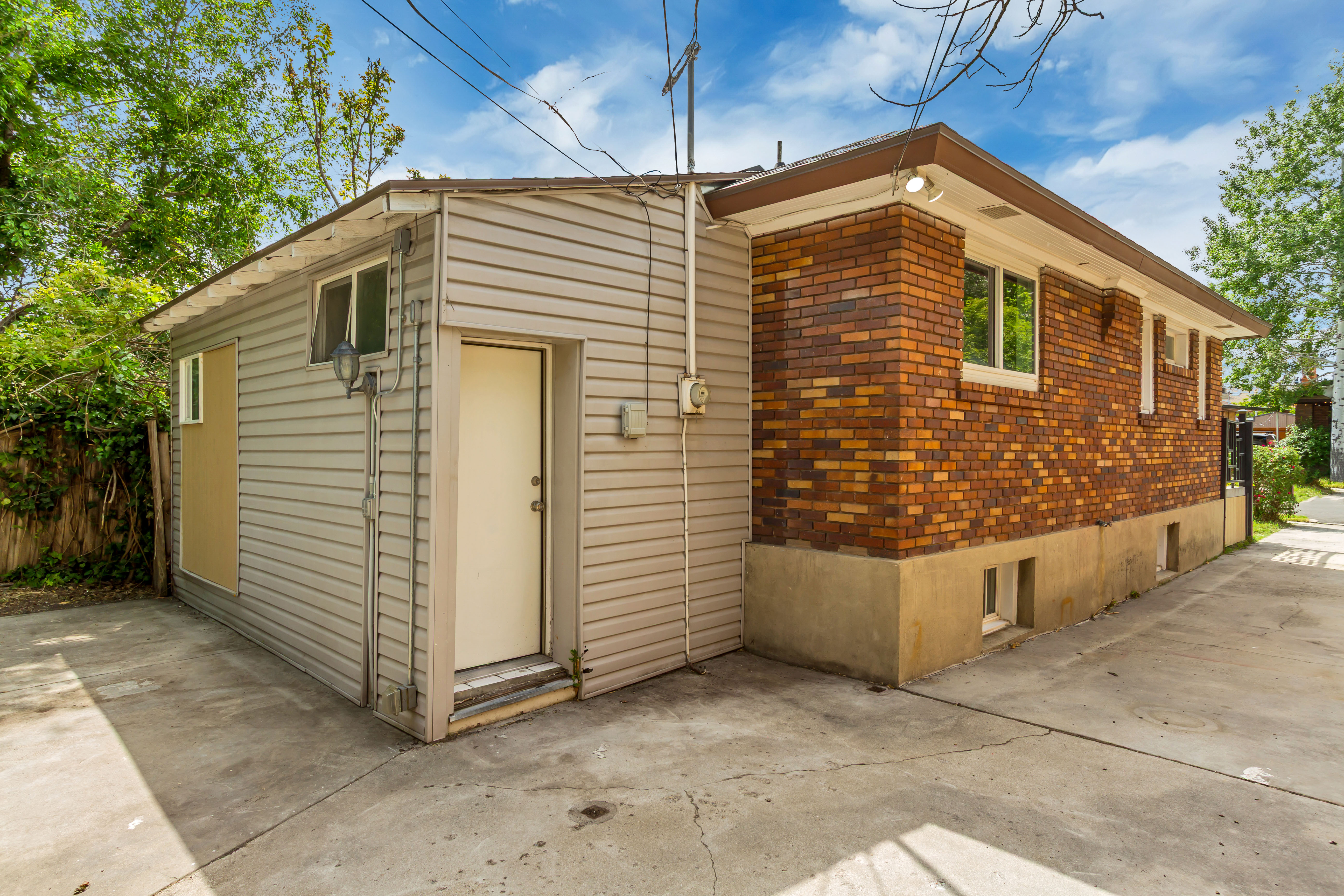 Exterior featuring a brick facade with a concrete foundation, horizontal siding, and multiple windows