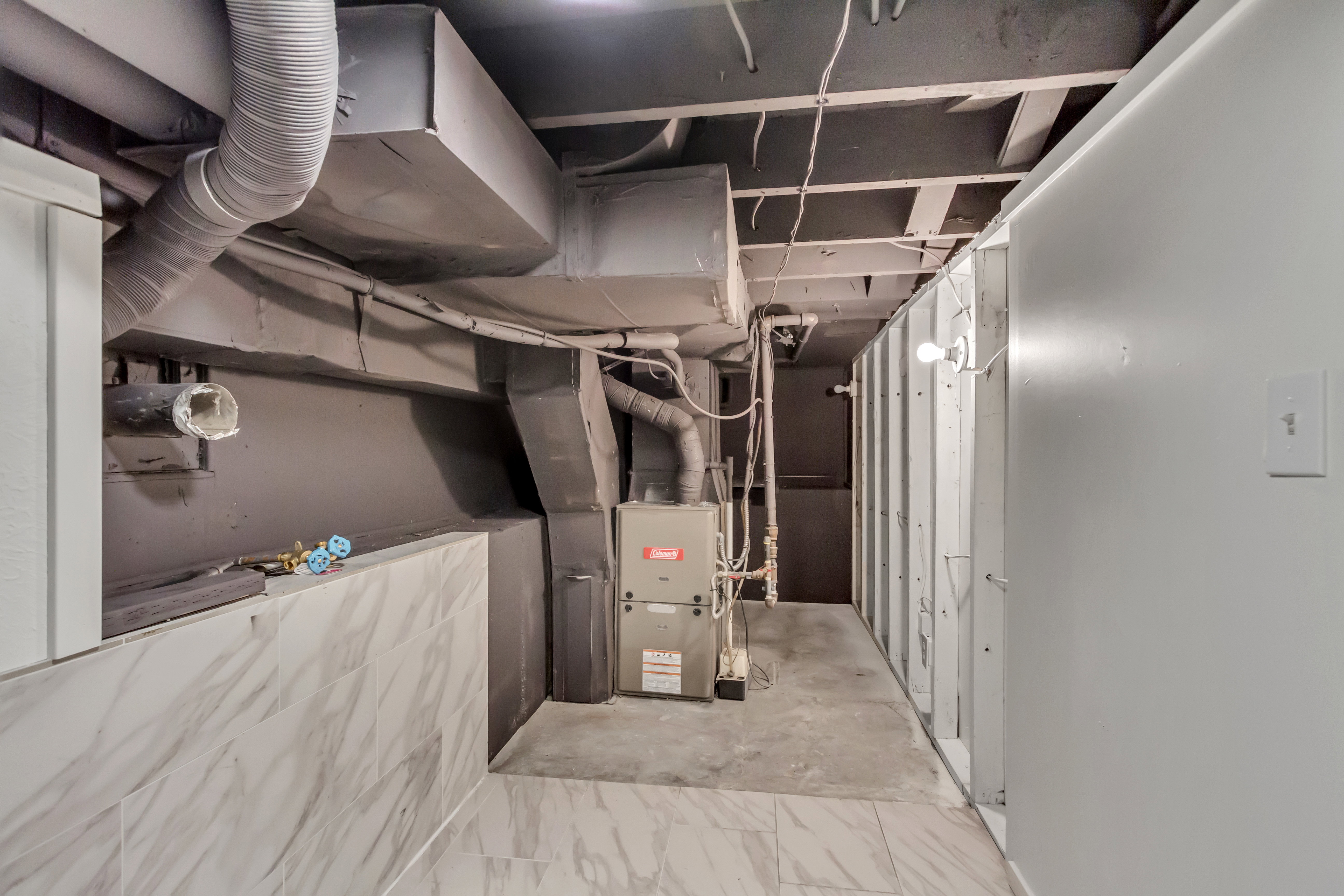 Utility room featuring exposed ceiling joists, overhead ductwork, a central heating unit, and a concrete floor