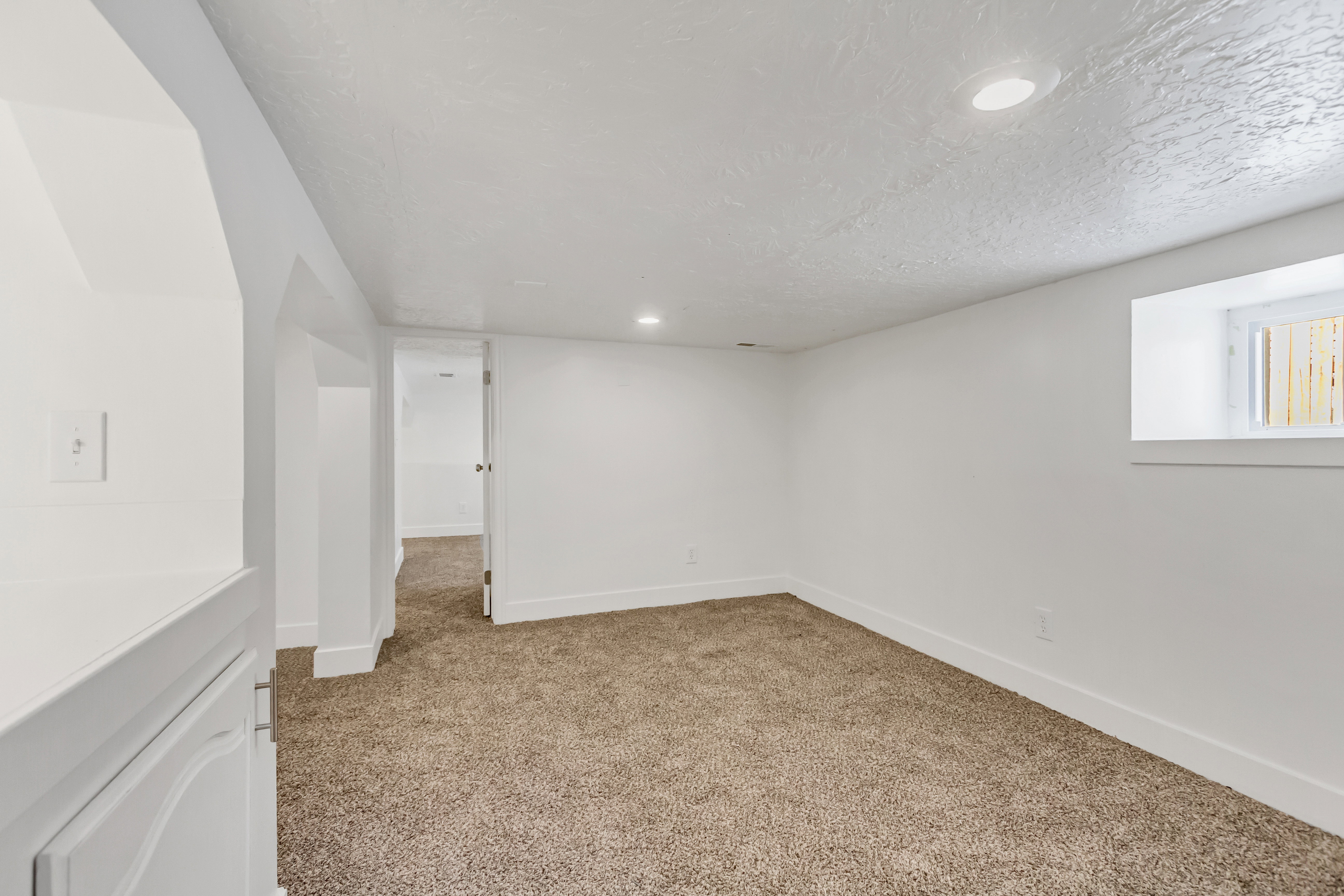 Spacious room featuring neutral carpet flooring, white walls, and recessed lighting