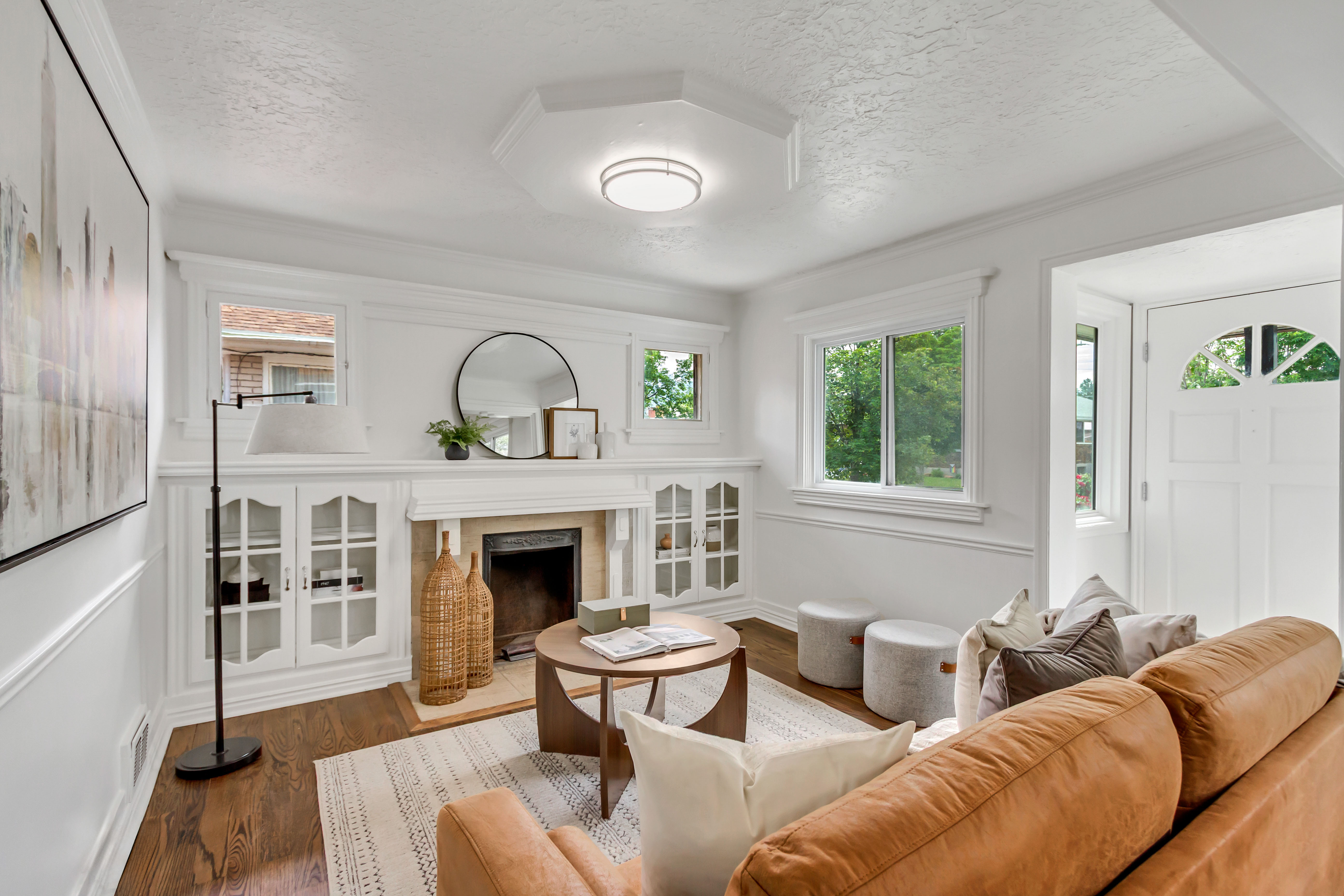 Living area featuring a fireplace with a mantel, built-in cabinetry, wood-finish flooring, and a white paneled entry door
