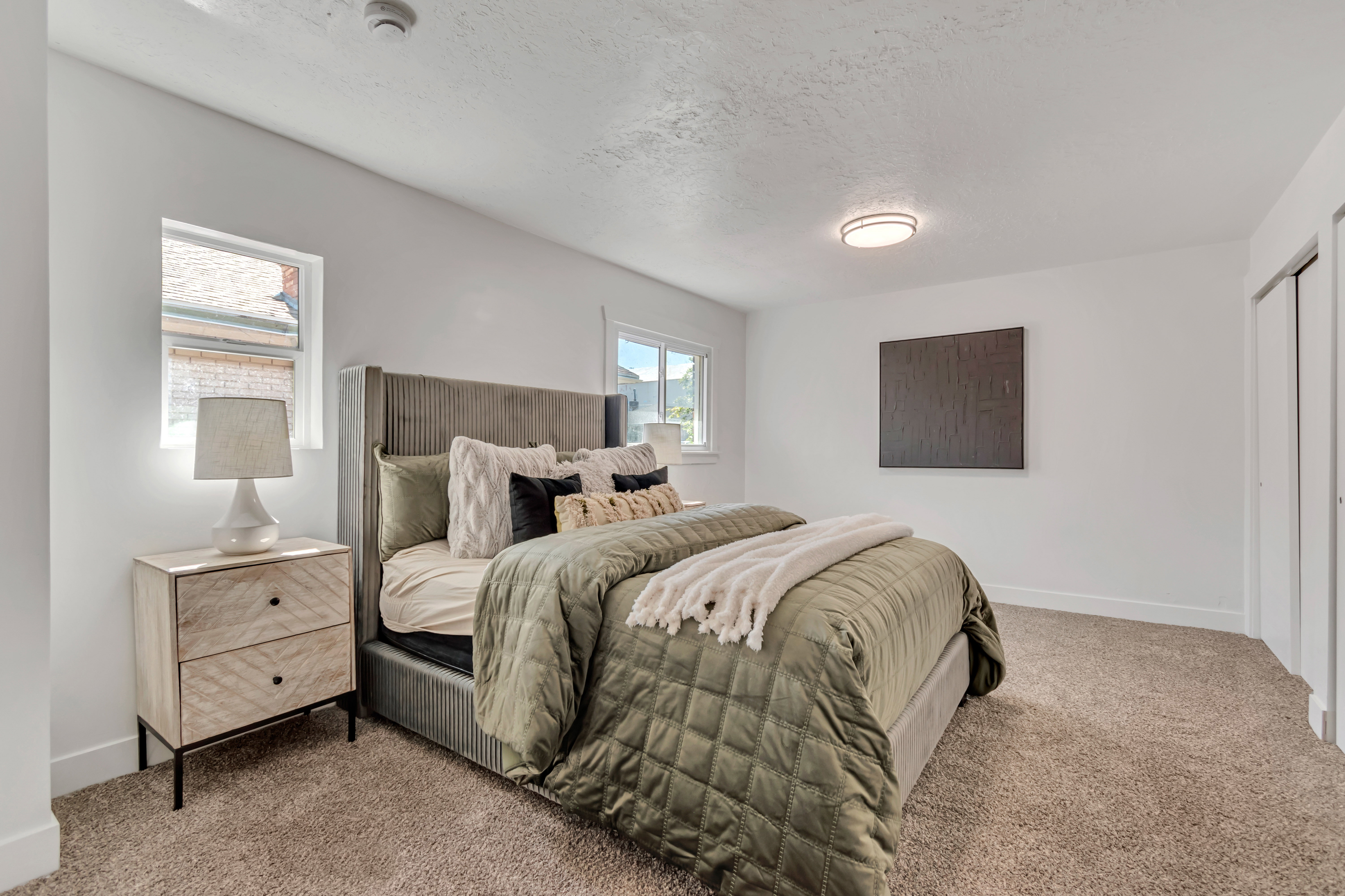 Carpeted bedroom with white walls, a single window, and a built-in closet with sliding doors