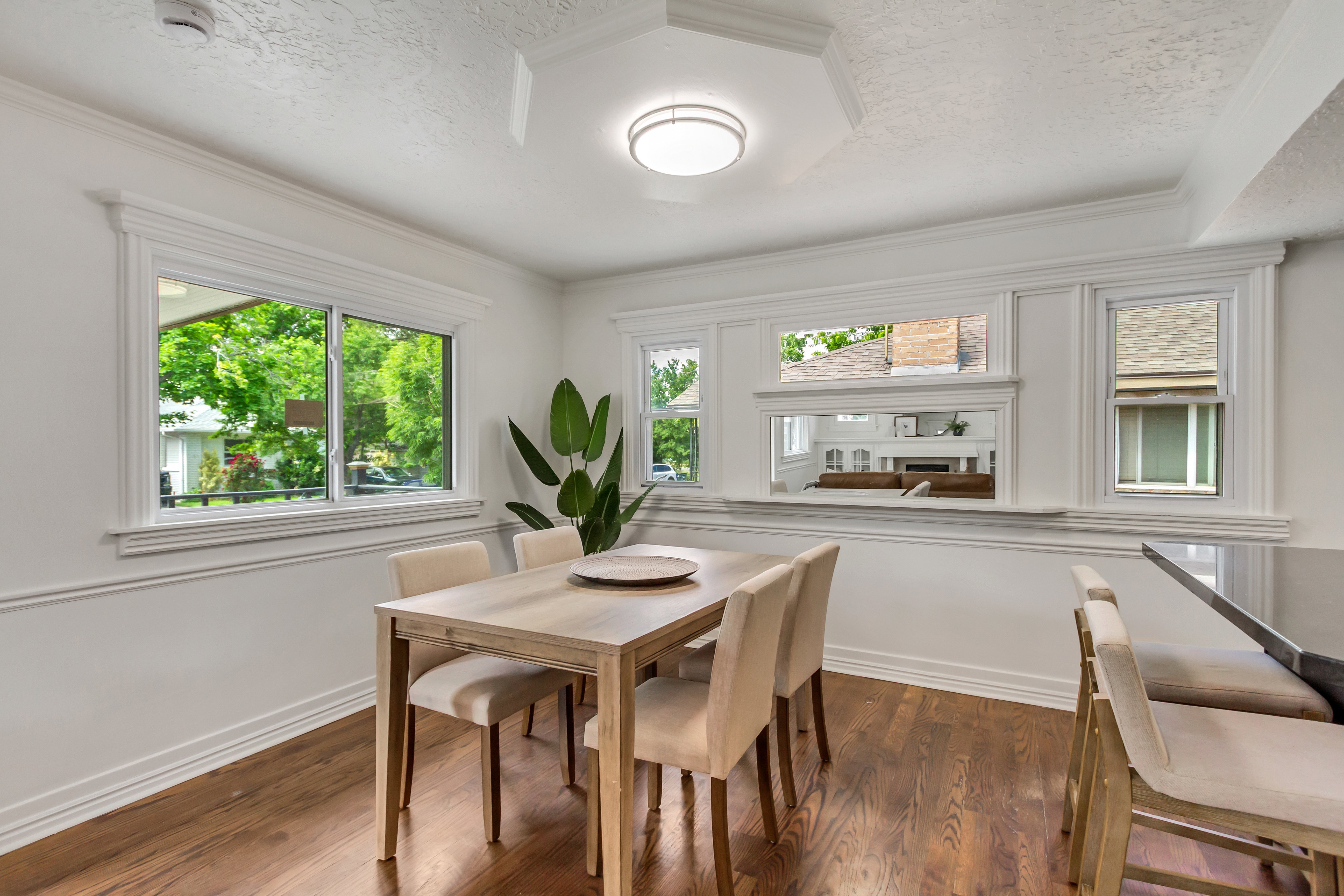 Dining area featuring rich wood-finish flooring, extensive white trim work, and multiple windows providing natural illumination