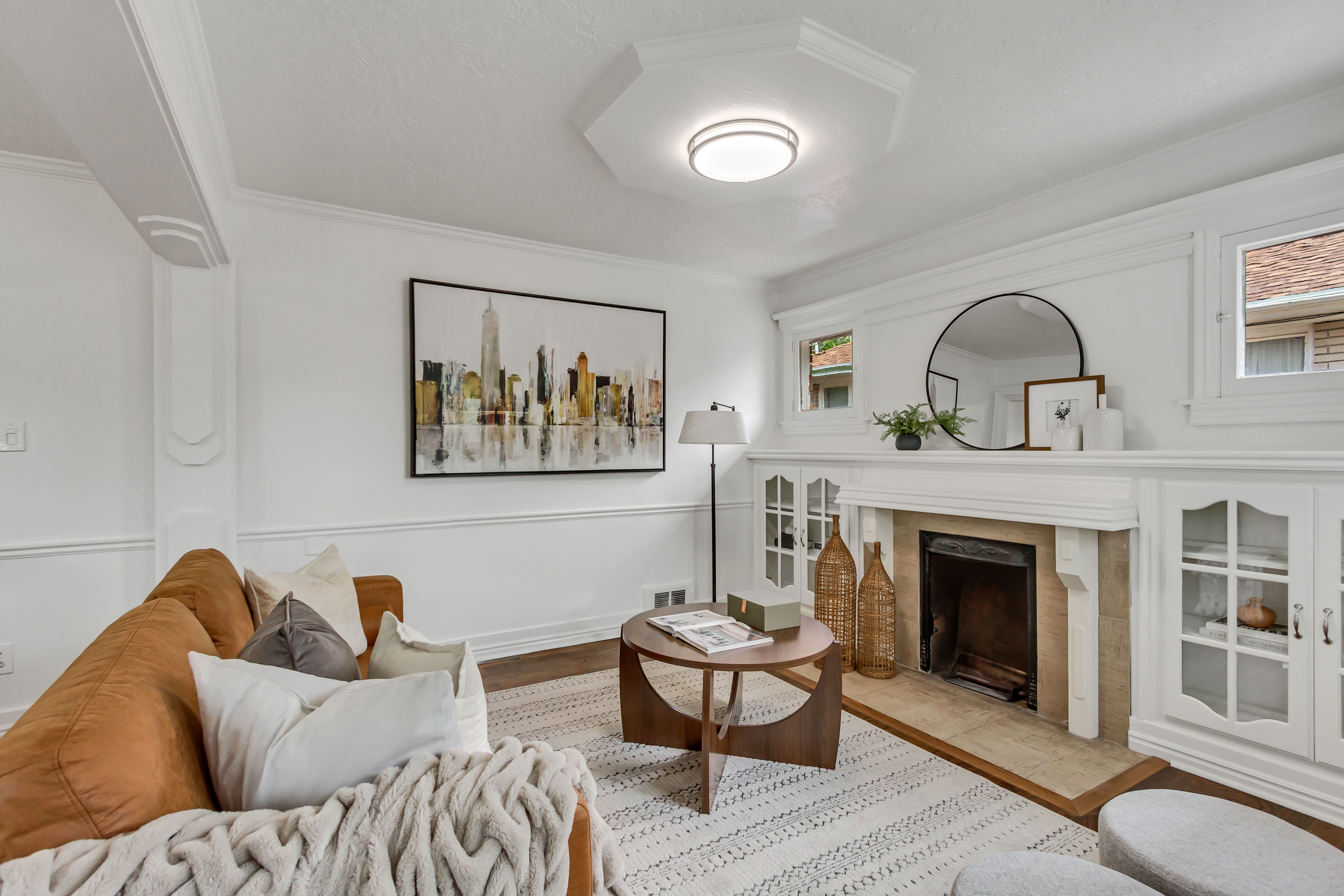 Living area featuring a stone-surround fireplace with a wood mantel, built-in cabinetry with glass-front doors, and crown molding