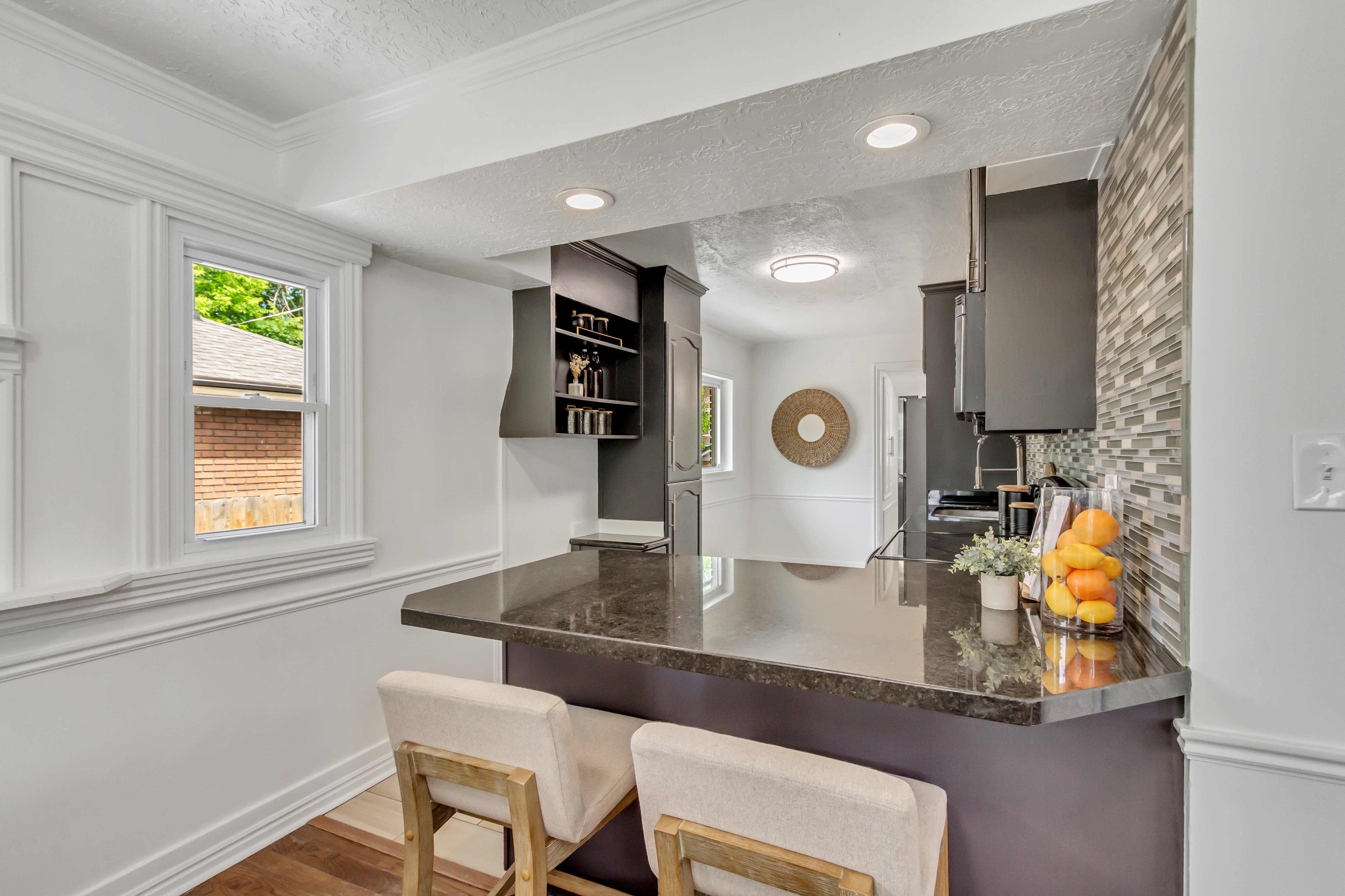 Breakfast bar featuring a polished dark countertop, a decorative tile backsplash, recessed lighting, and rich dark cabinetry