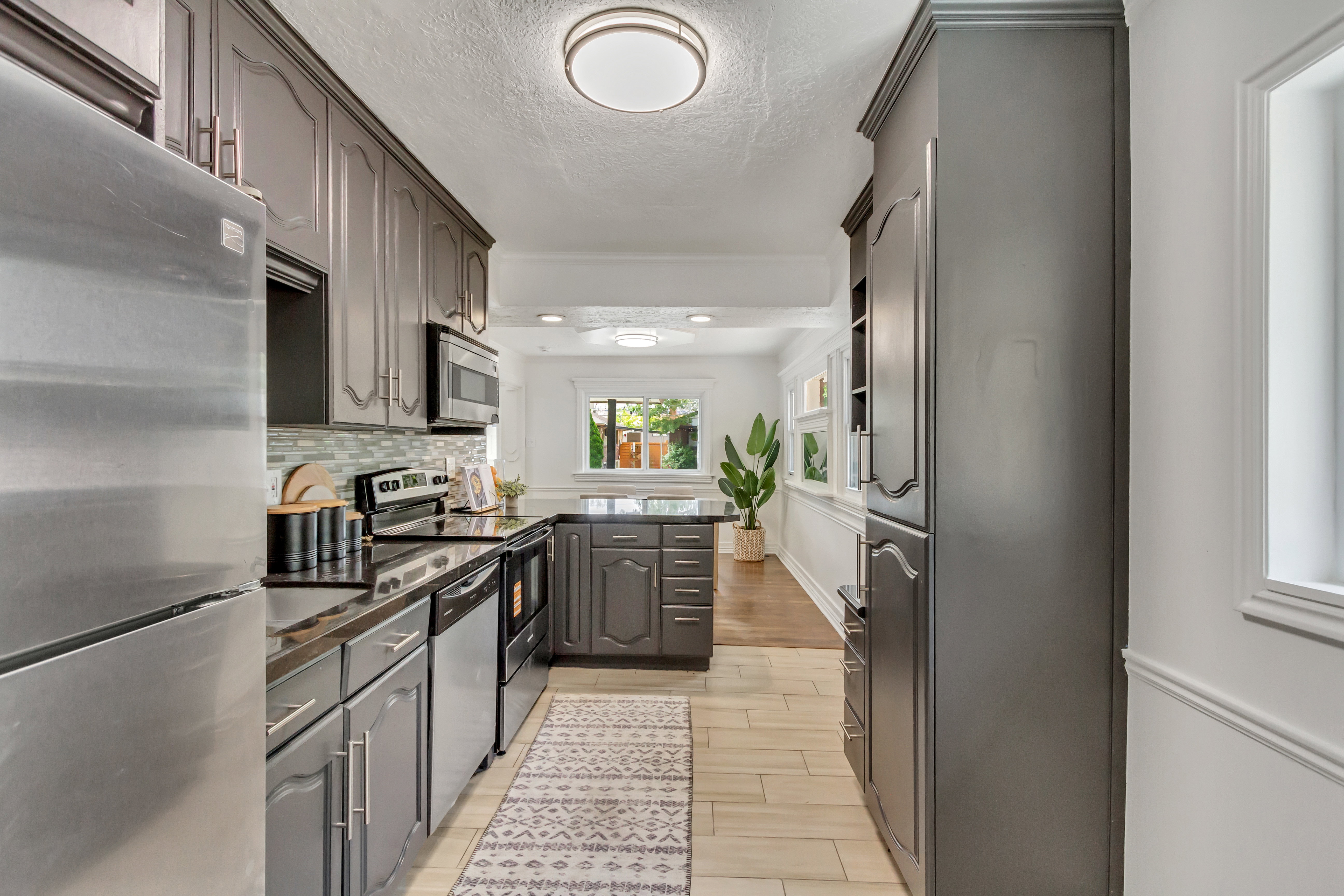 Kitchen featuring dark cabinetry, stainless steel appliances, black countertops, and a subway tile backsplash