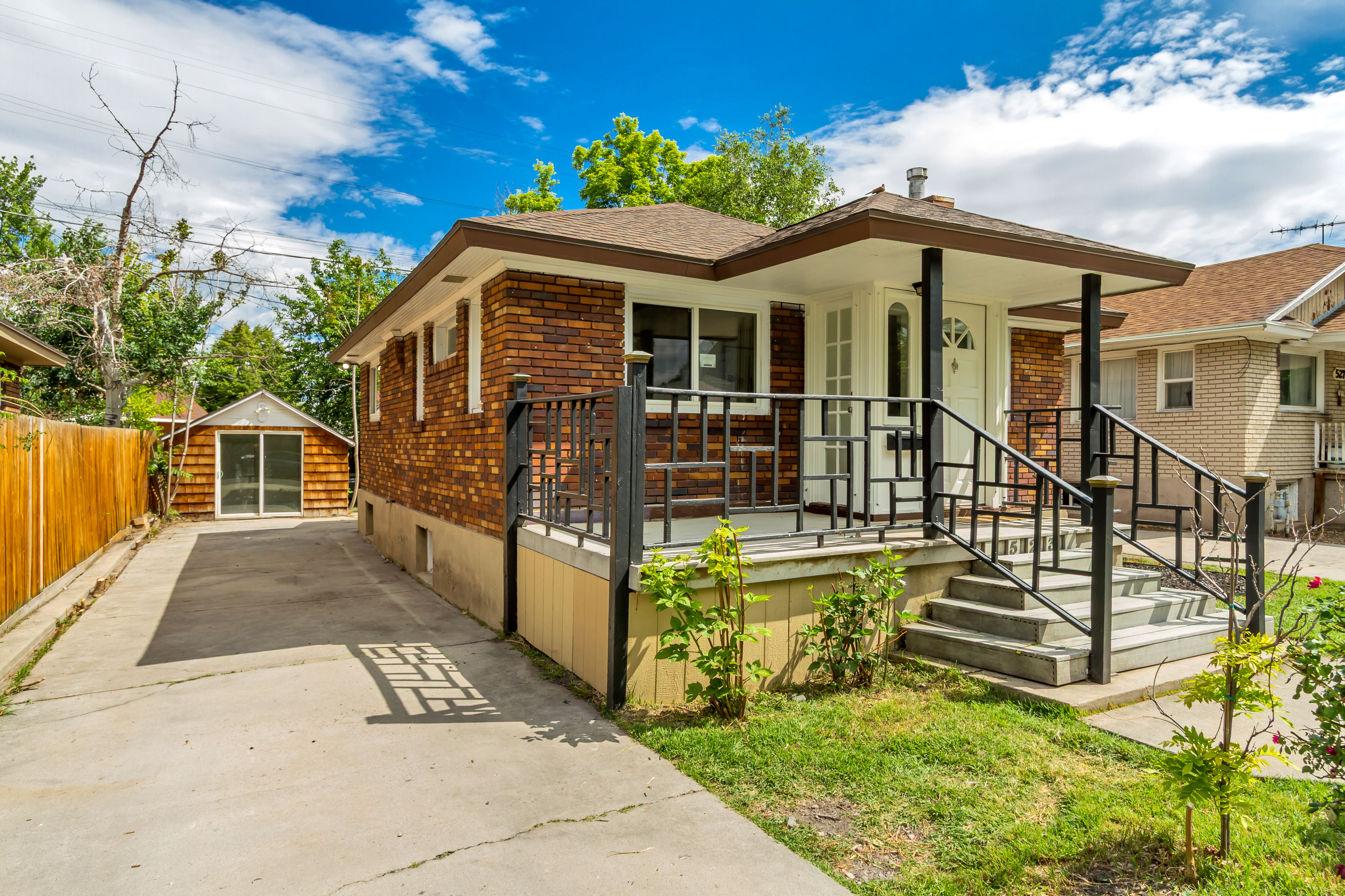 Brick-clad residence featuring a covered front porch with decorative iron railings