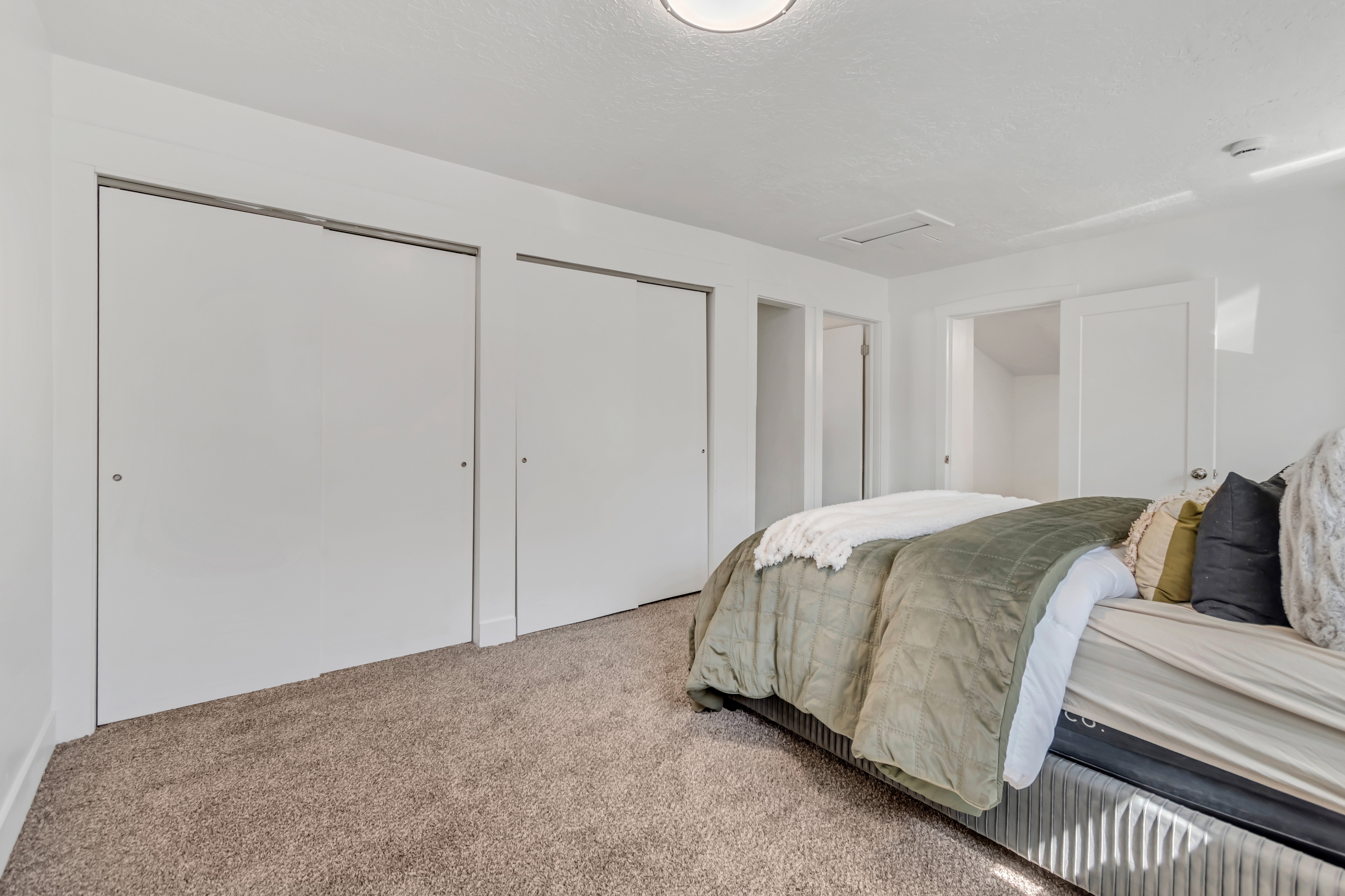 Carpeted interior space featuring white walls, two bifold closet doors, and recessed lighting