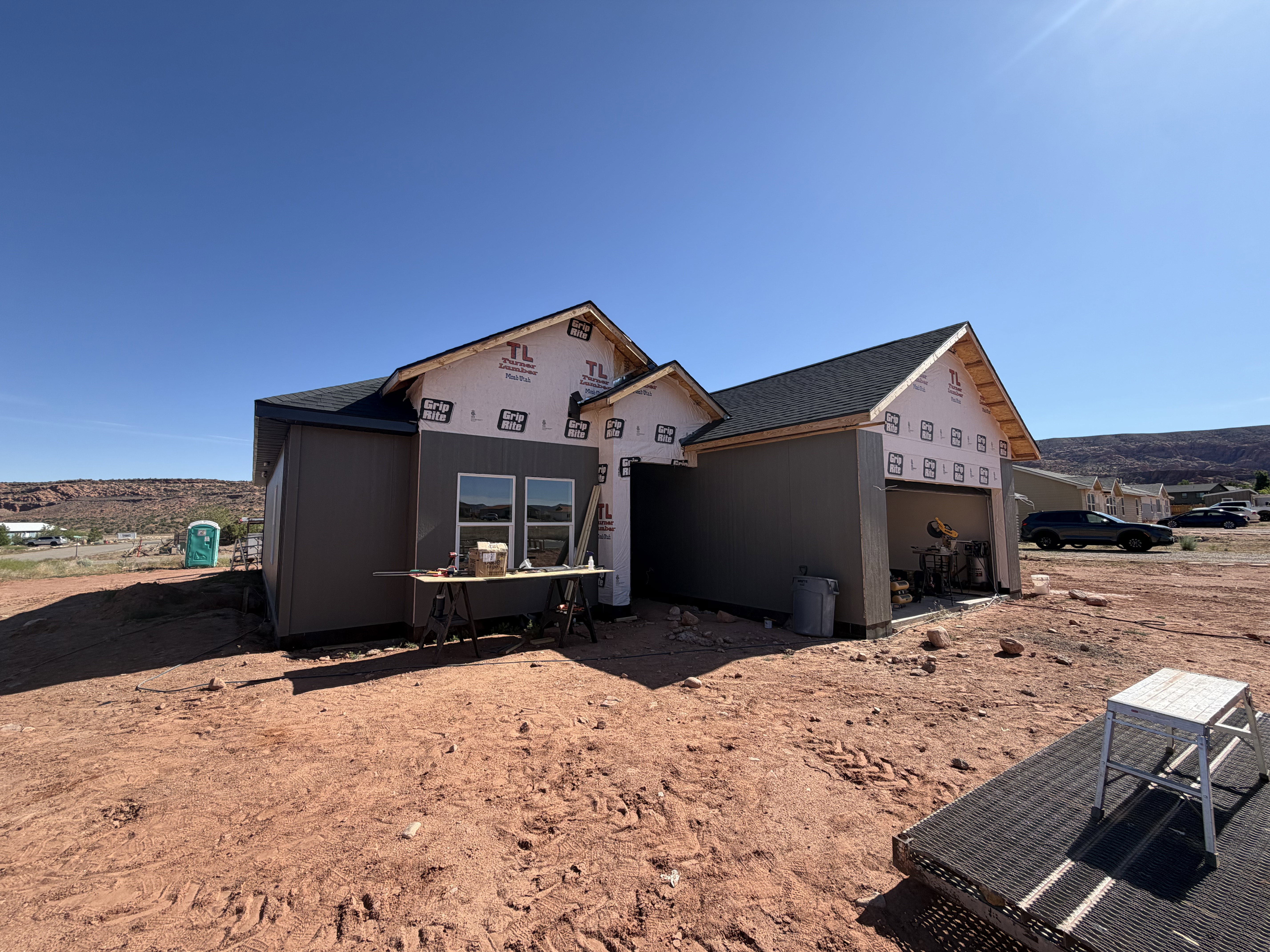 UNDER CONSTRUCTION residence featuring a dark shingle roof, siding, standing seam metal and a two-car garage