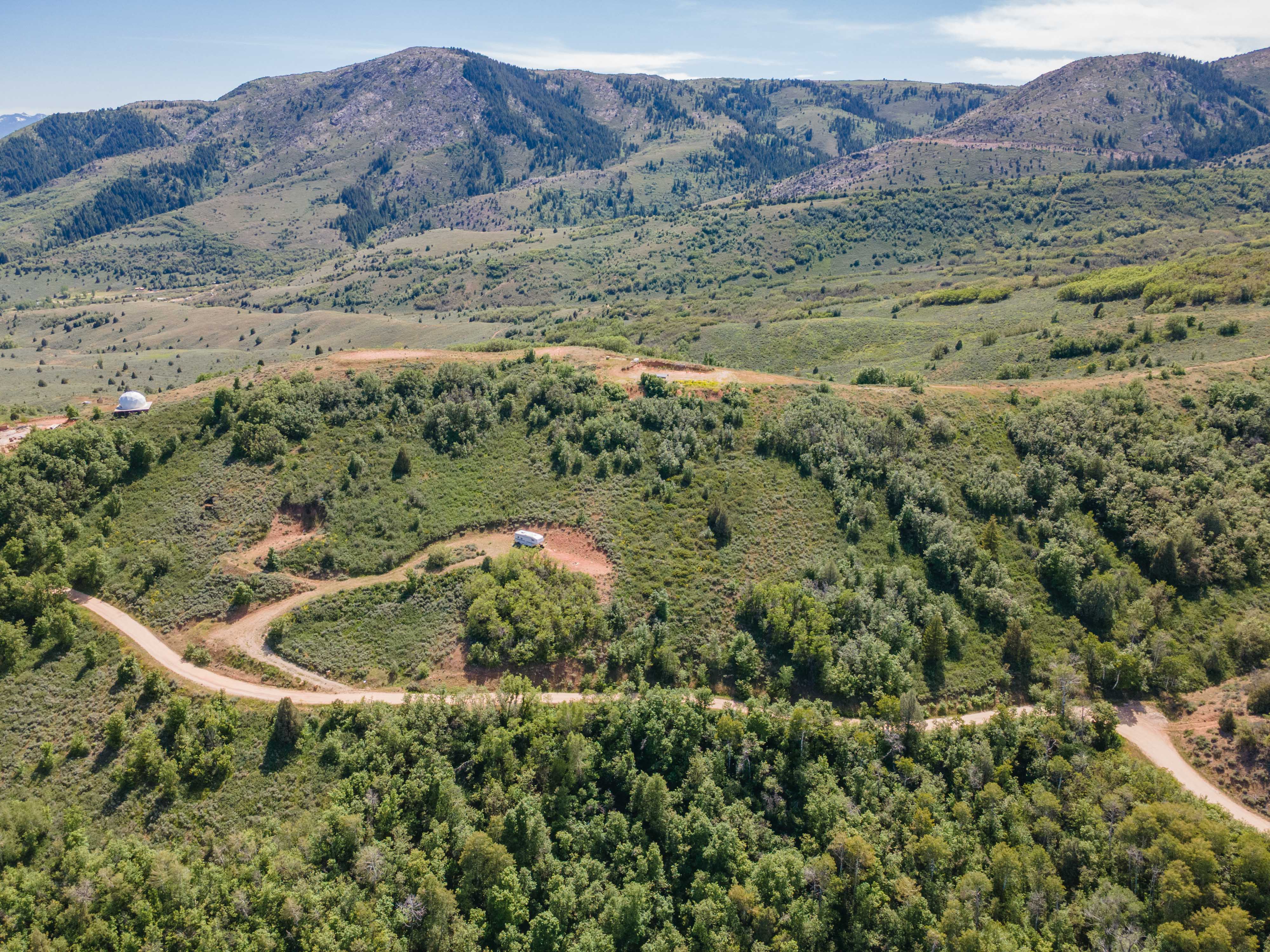 Expansive mountain landscape featuring varied terrain with verdant foliage and distant peaks