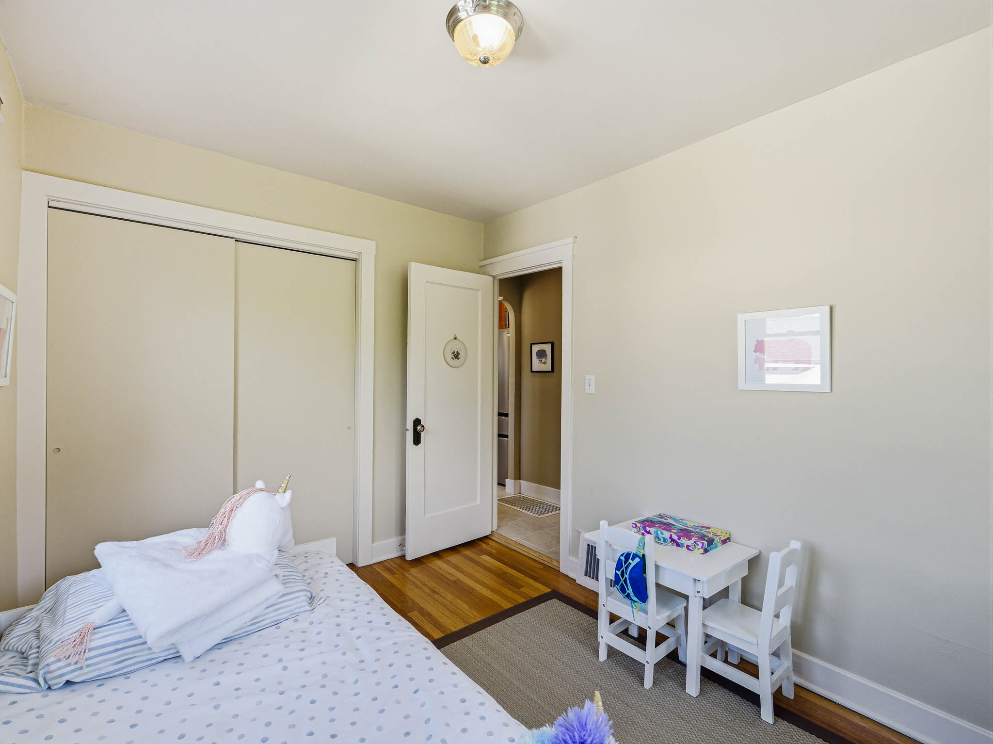 Neutral-toned room featuring wood-finish flooring, a flush-mount ceiling light fixture, and a white interior door
