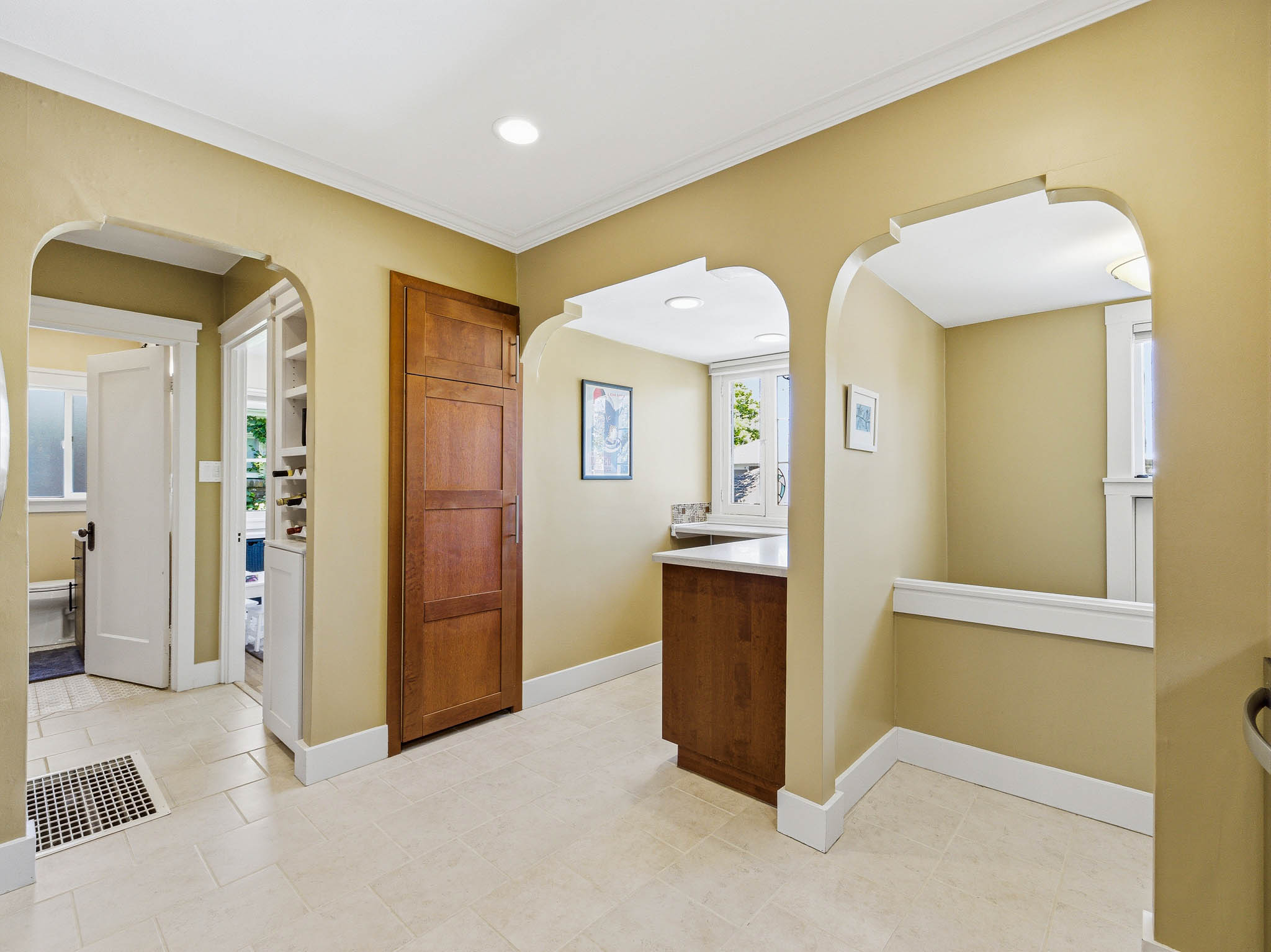 Cream-toned tile flooring throughout with decorative archways and crown molding