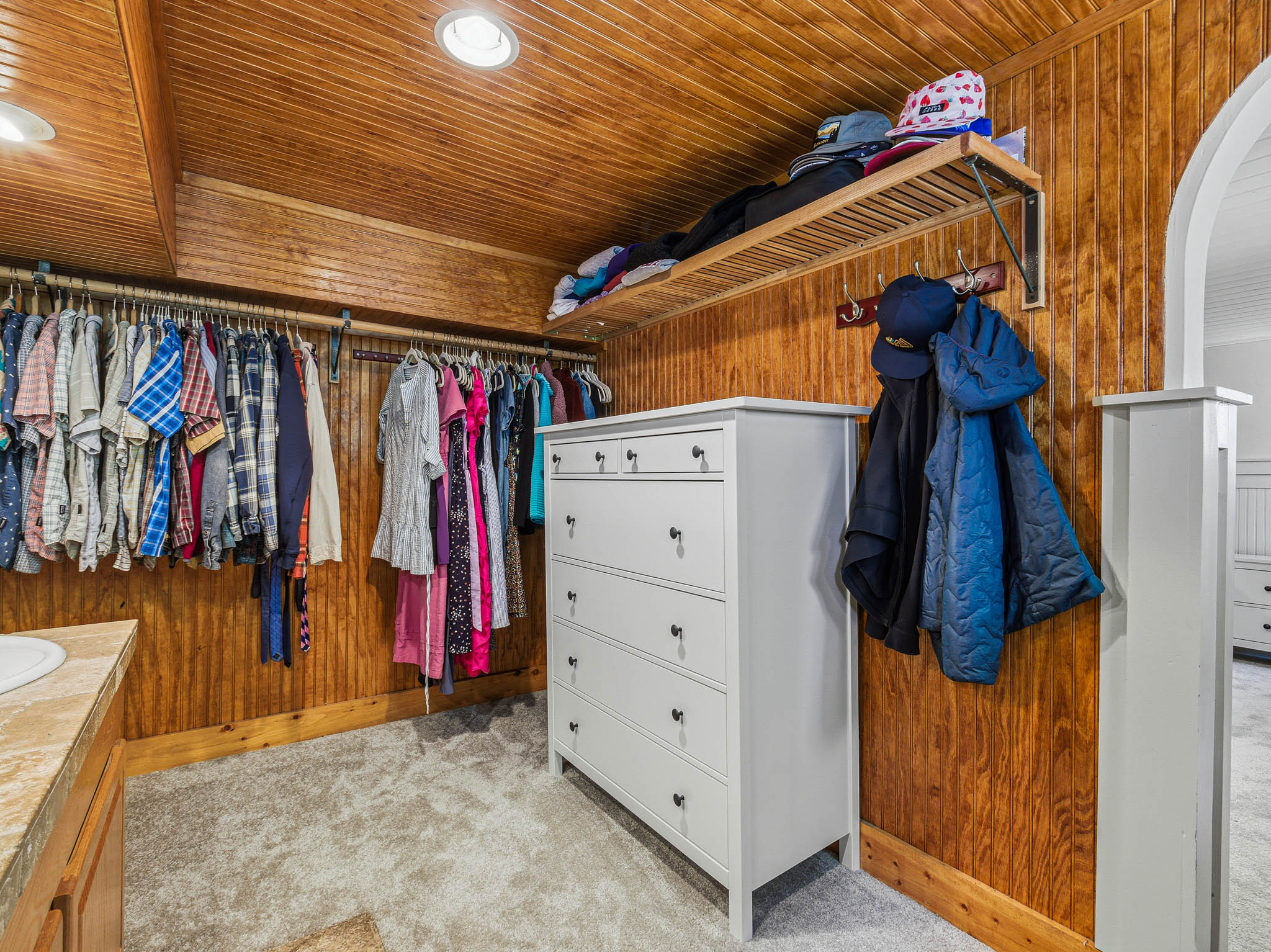 Spacious closet featuring wood-paneled walls and ceiling, recessed lighting, and soft carpet flooring