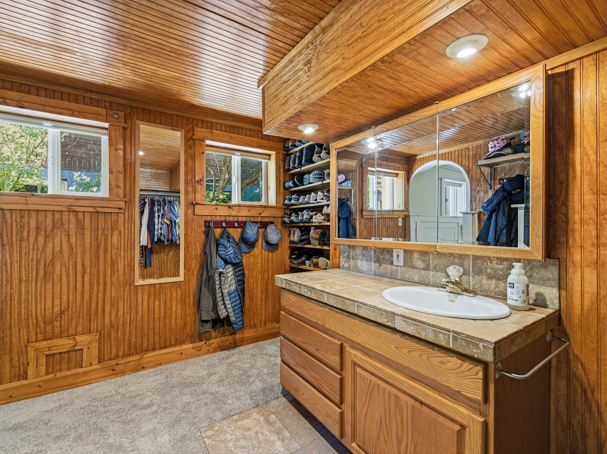Wood-paneled room featuring a vanity with an oval sink, tile countertop, and medicine cabinet