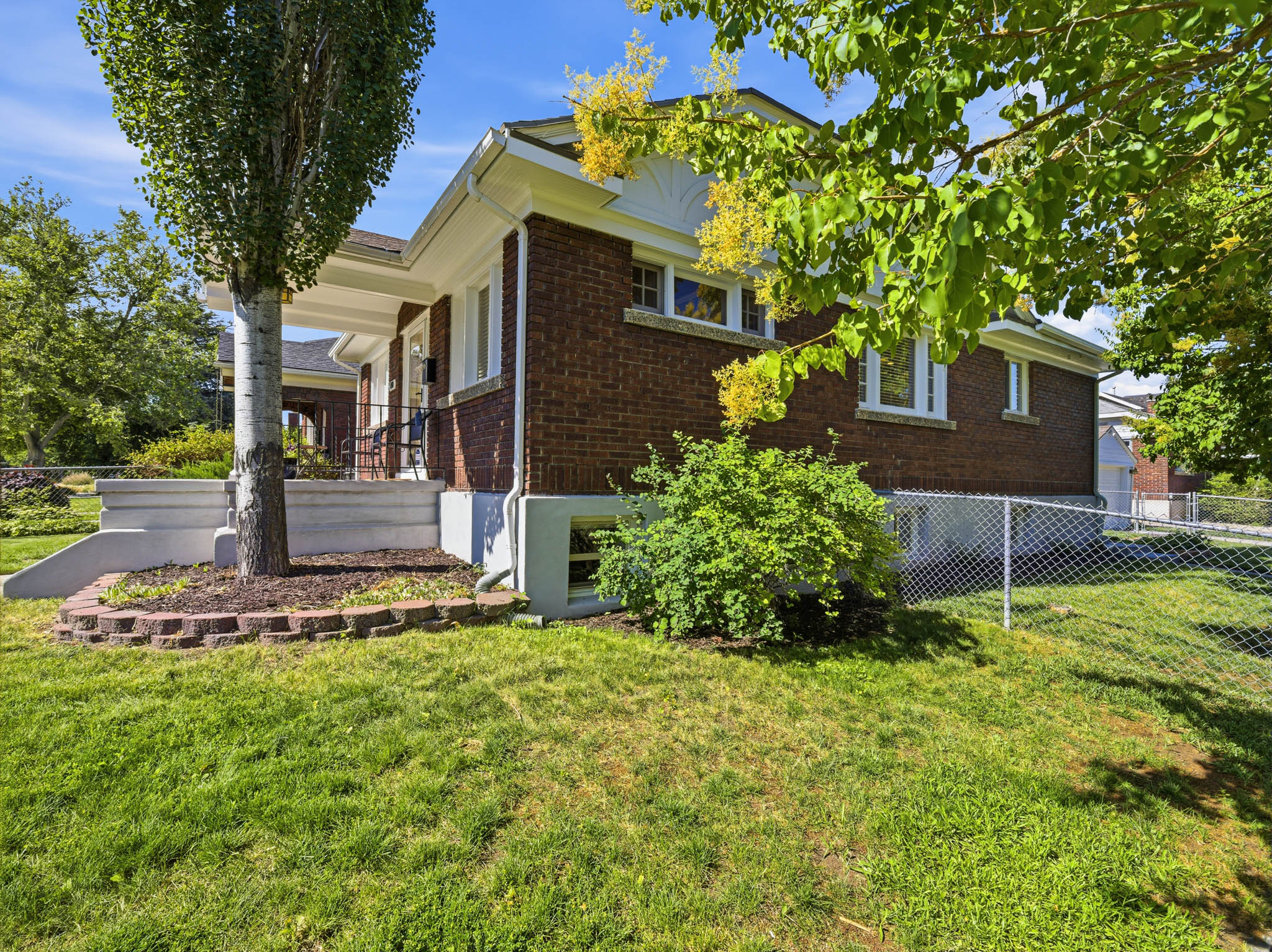 Brick exterior showcasing white trim, a covered porch, and a mature tree