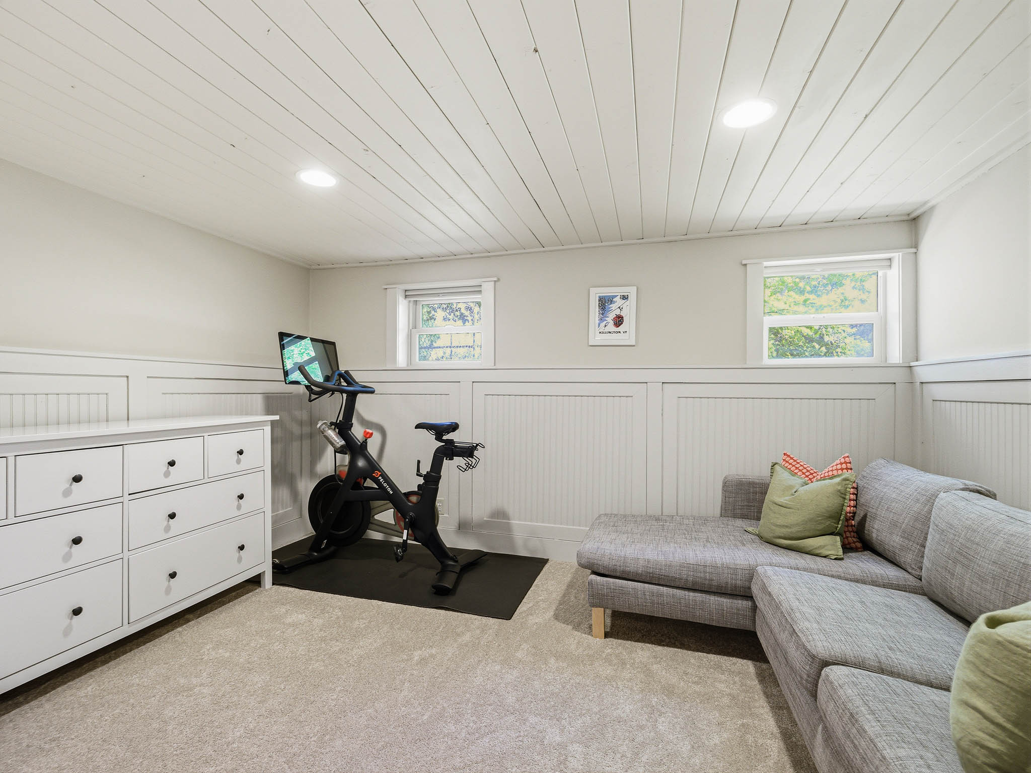 Finished room featuring light-colored carpeting, white beadboard wainscoting, and recessed ceiling lighting