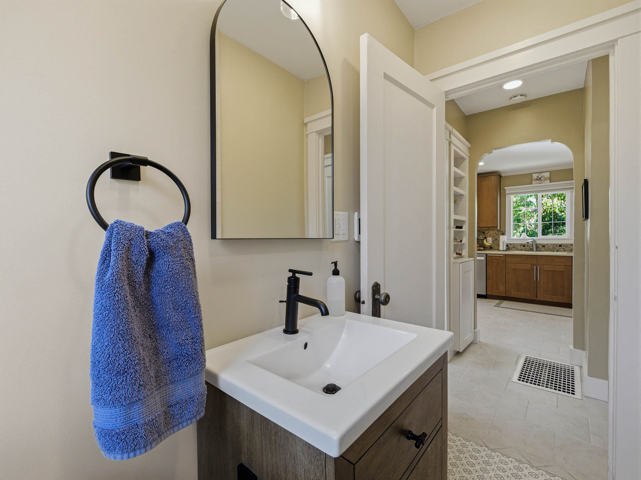 Bathroom vanity featuring a white rectangular sink, matte black faucet, and wood-finish cabinetry