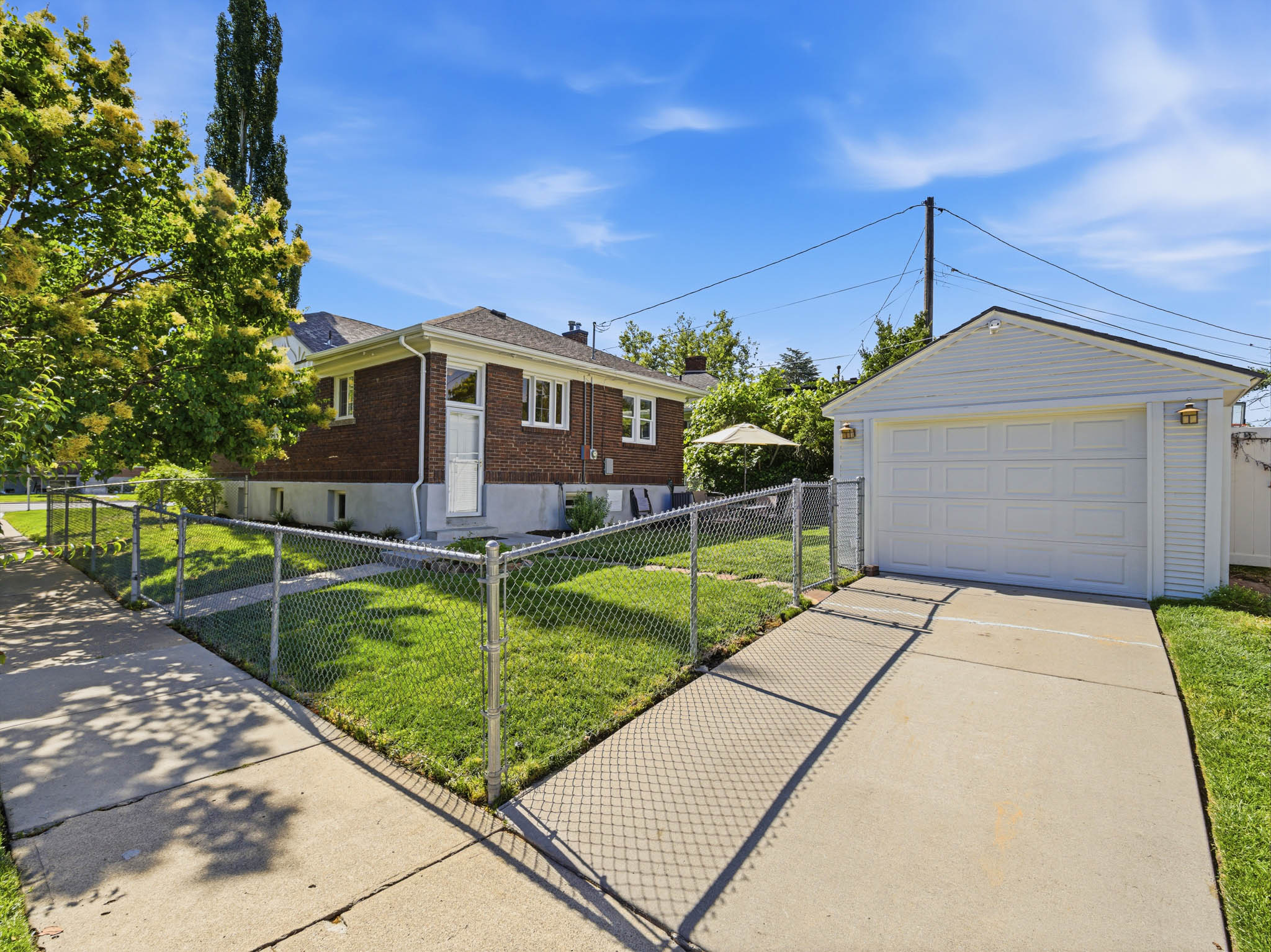 Detached garage with a paneled door, ample driveway space, and exterior lighting