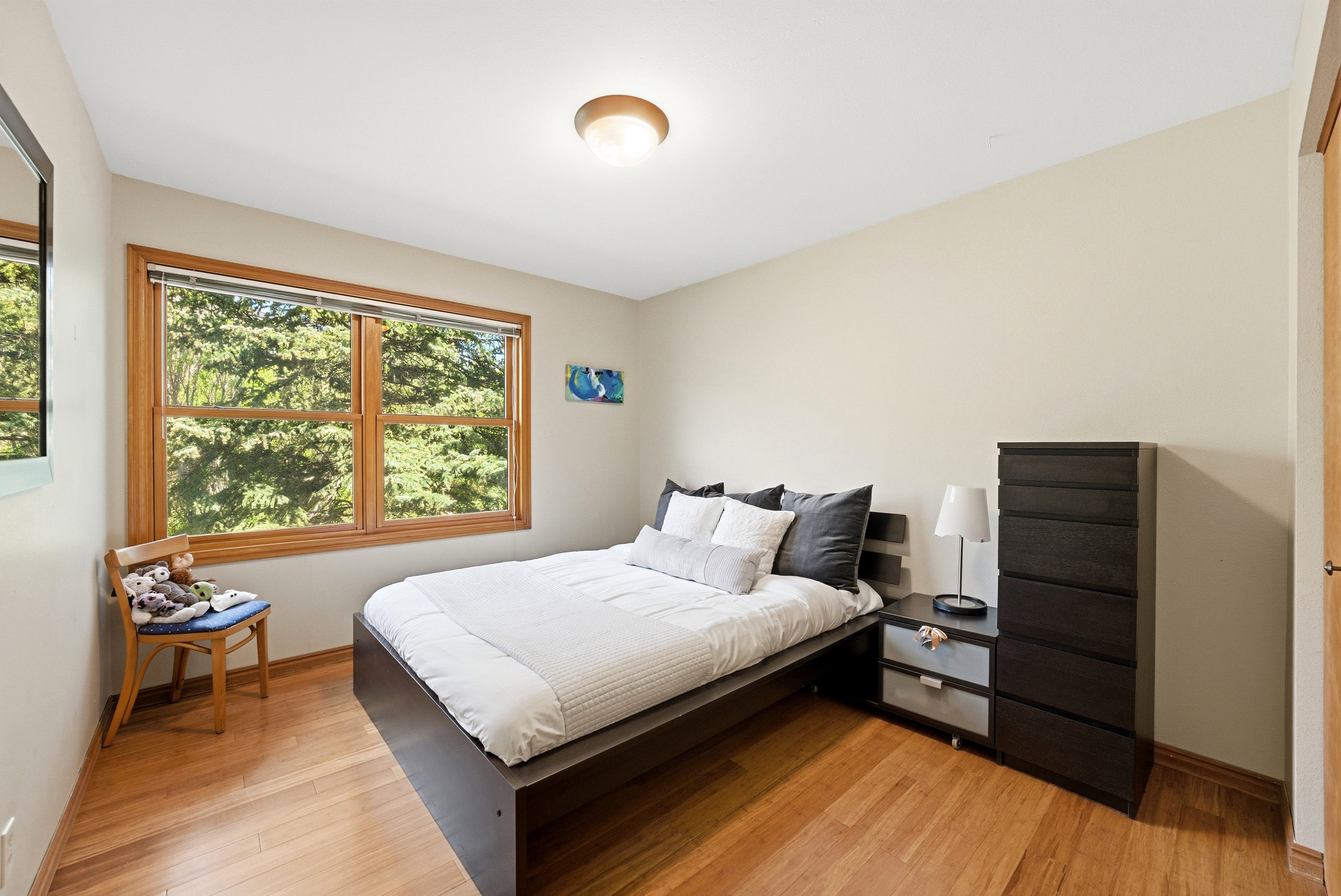 Bedroom featuring wood-finish flooring, a wood-framed window, and a flush-mount ceiling light