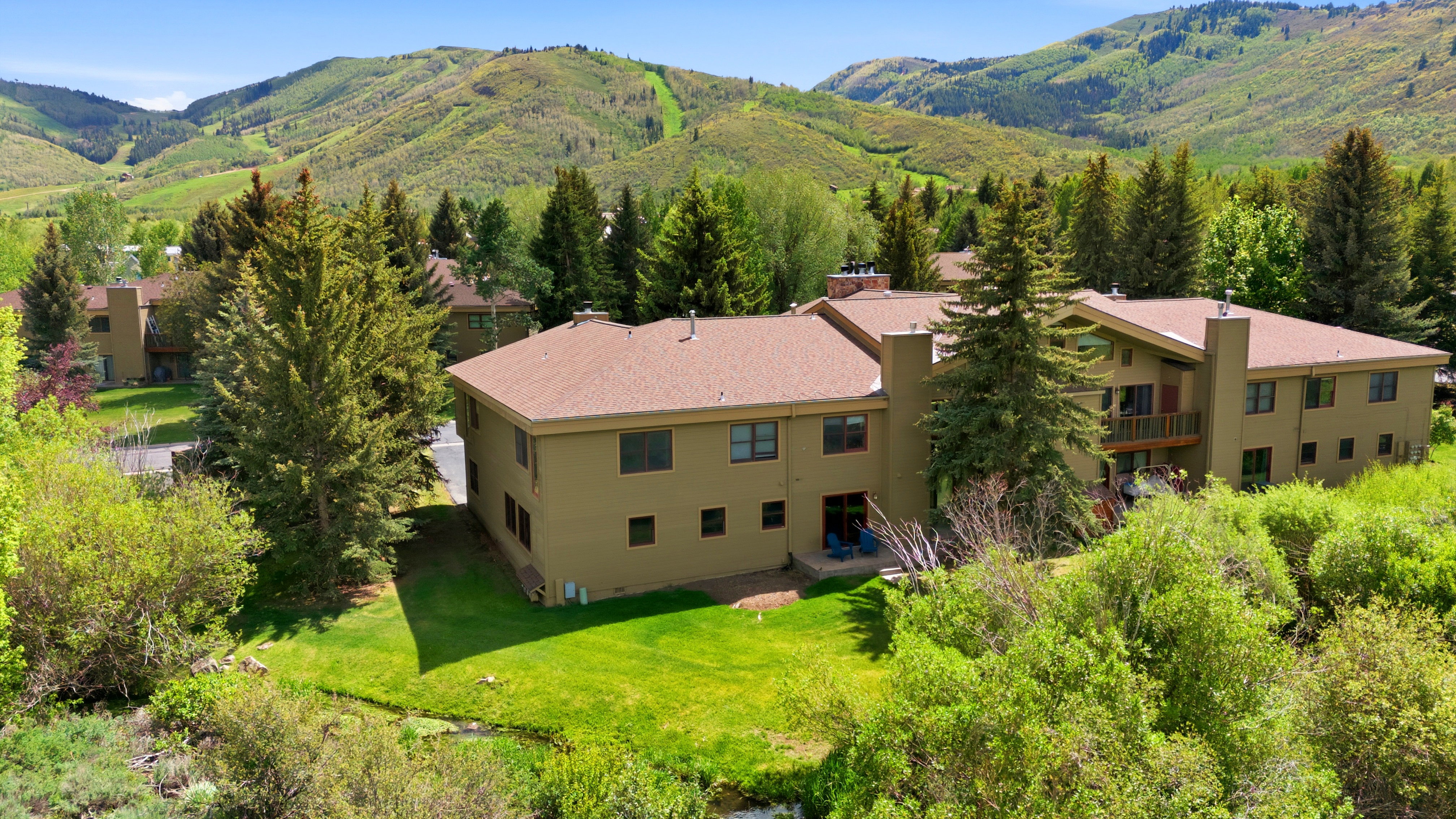 Contemporary multi-story exterior with a brown shingle roof, multiple chimneys, and a prominent balcony
